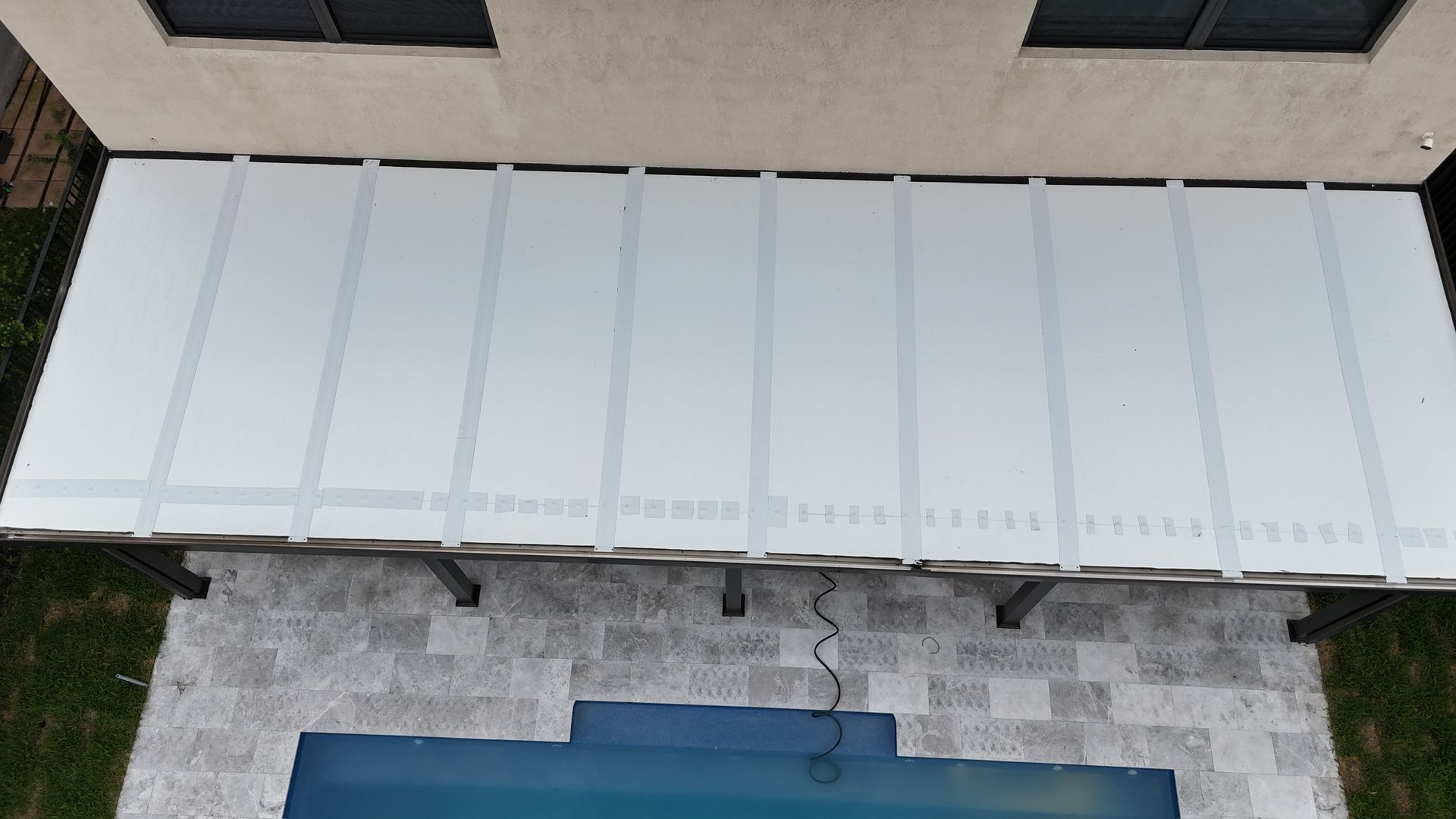 An aerial view of a white roof over a swimming pool.