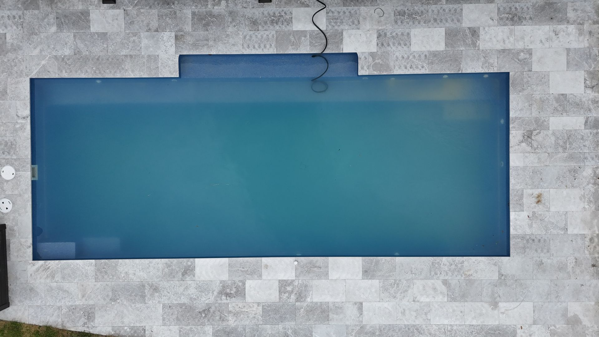 An aerial view of a large swimming pool surrounded by tiles.