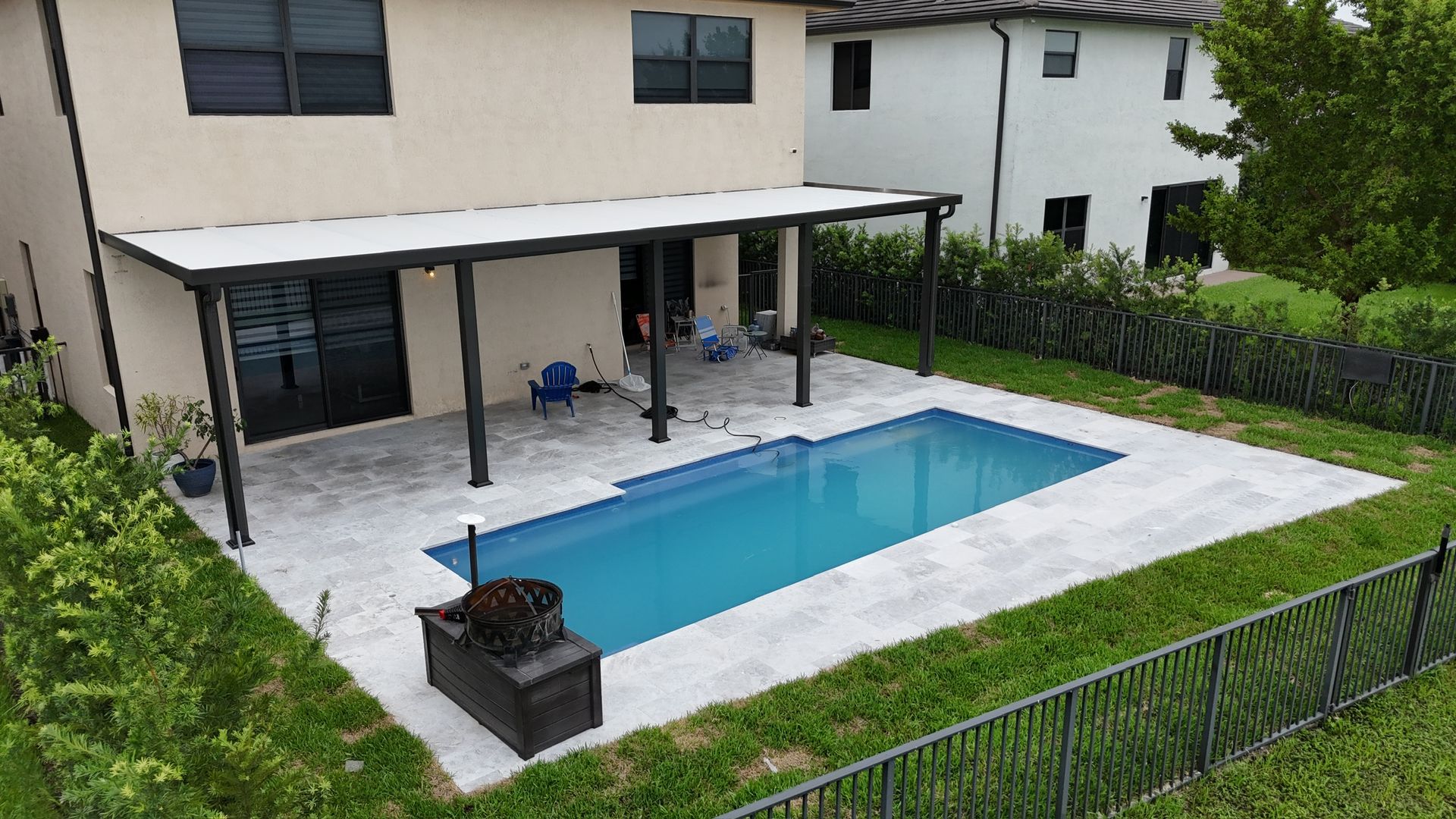 A large swimming pool is in the backyard of a house.
