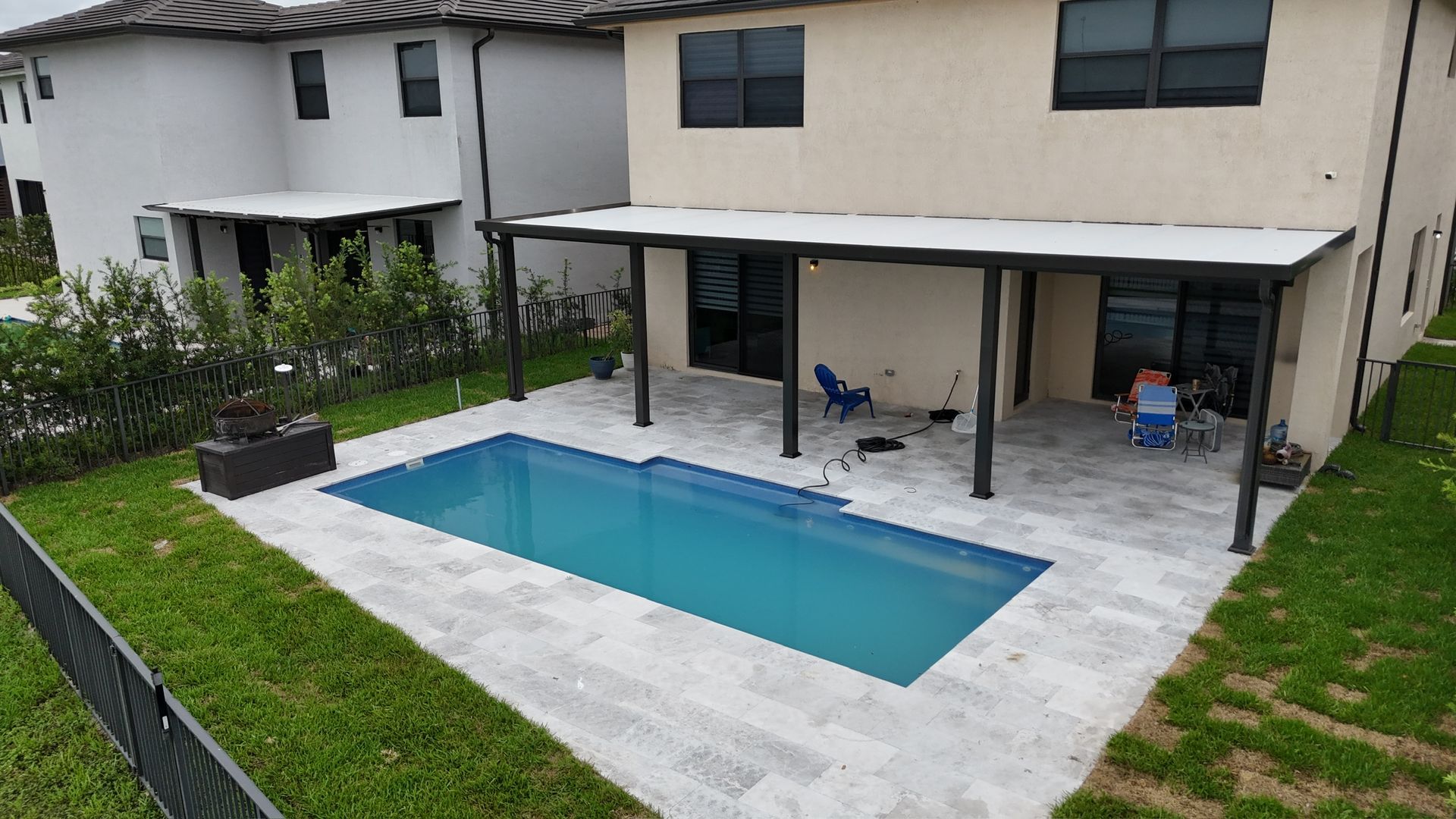 A large swimming pool is in the backyard of a house.