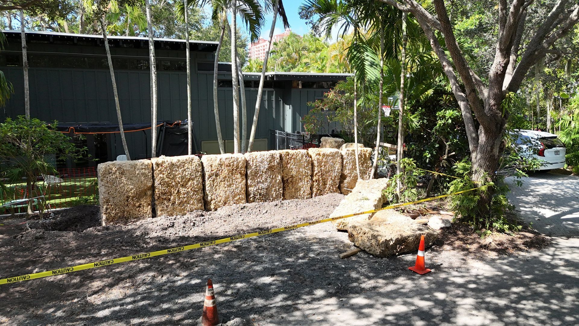 A large pile of hay bales is sitting in front of a house.