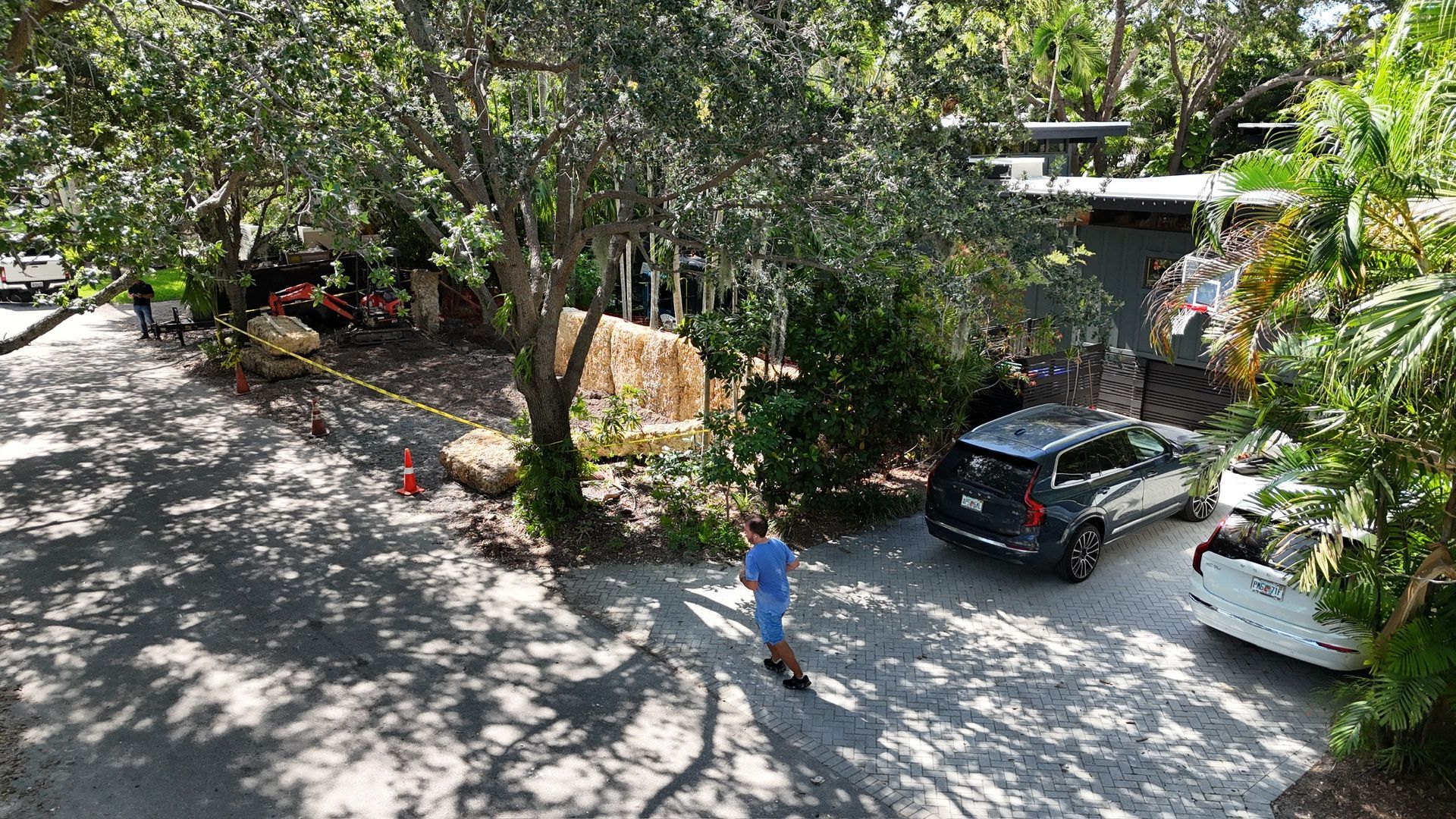 An aerial view of a man walking down a driveway next to a house.