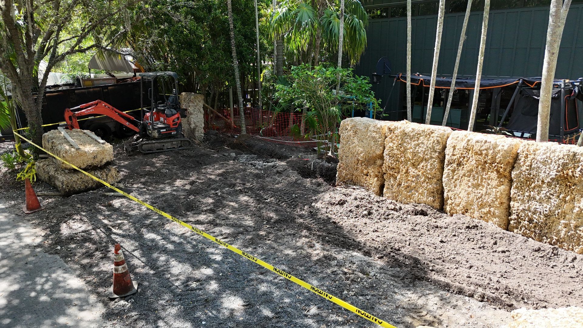 A large pile of hay bales is sitting in the middle of a dirt field.