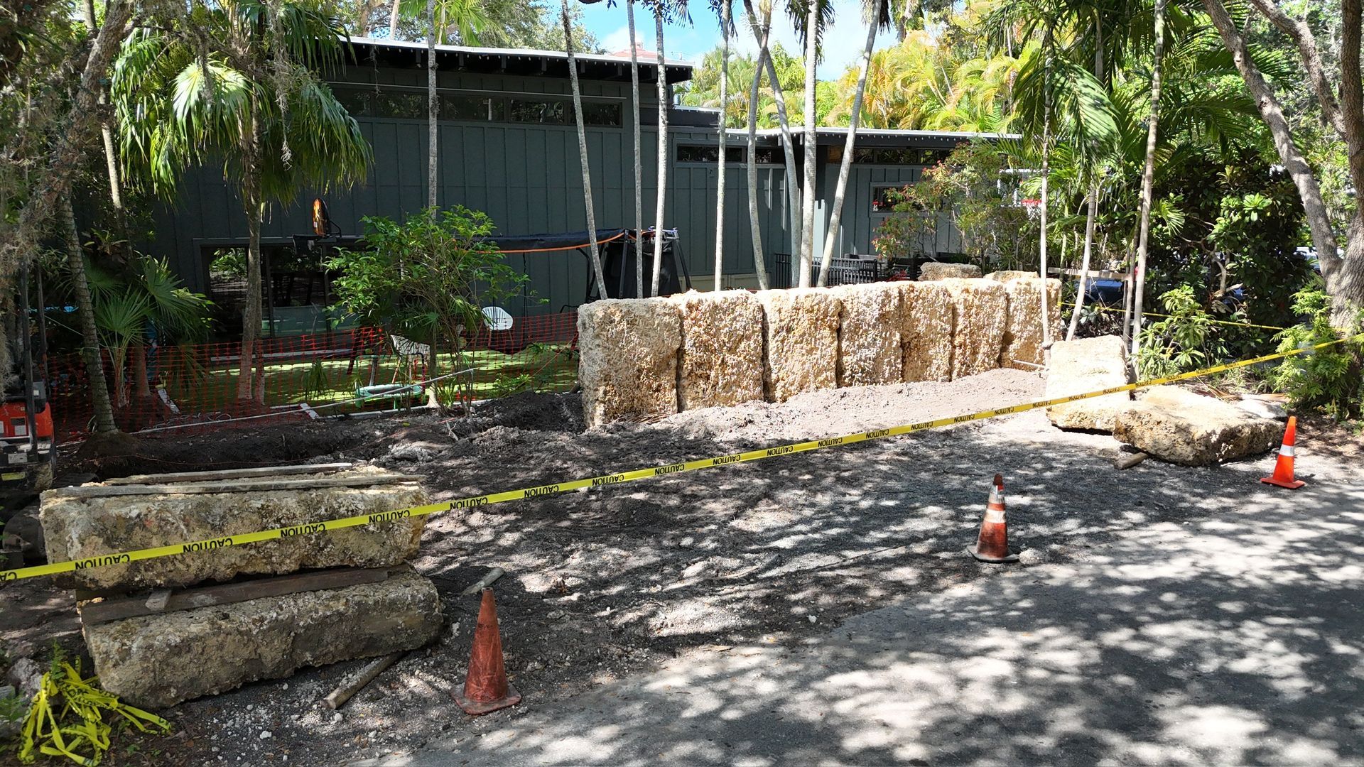 A large rock wall is being built in front of a house.