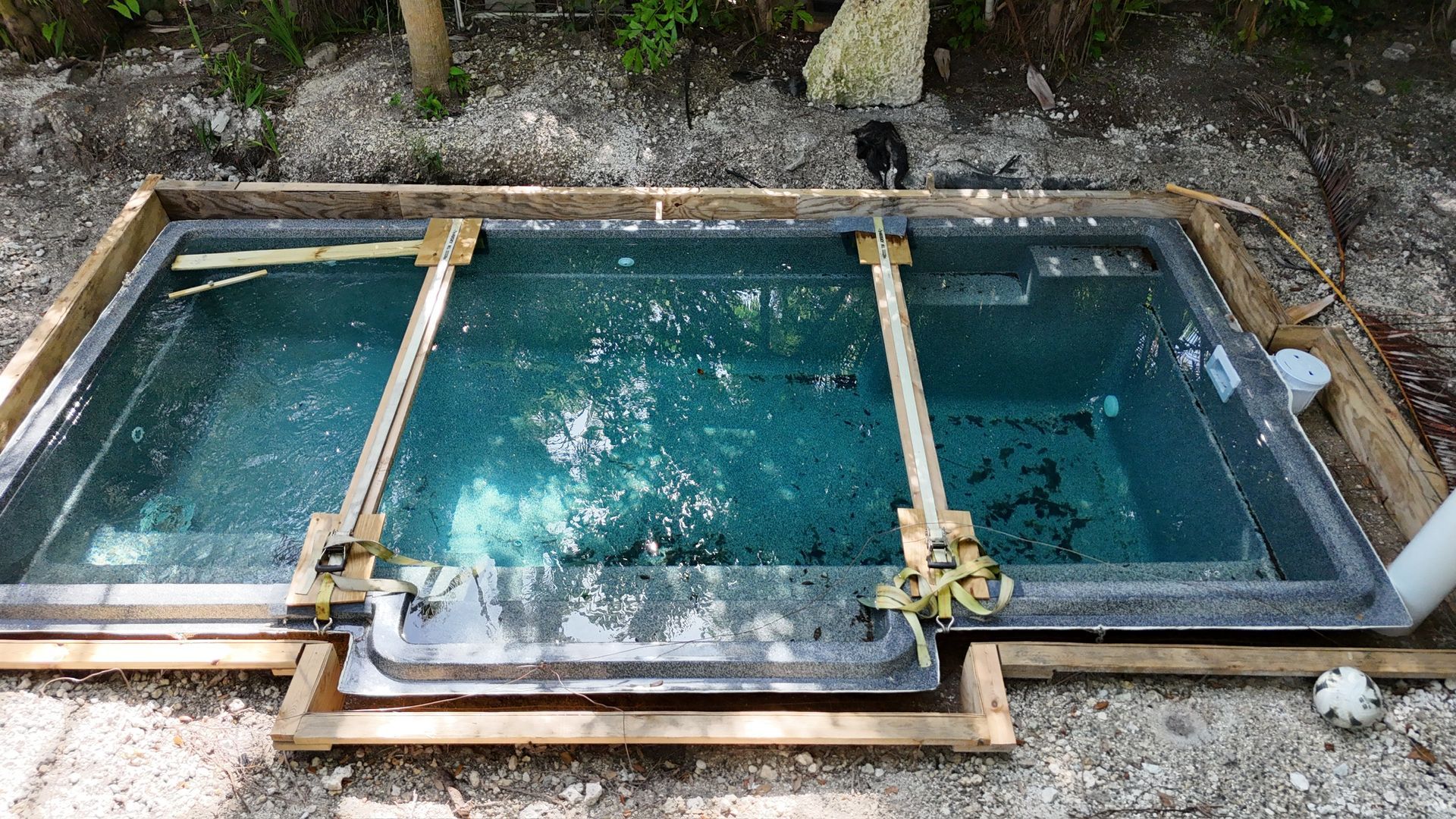 A small swimming pool is being built in the dirt.