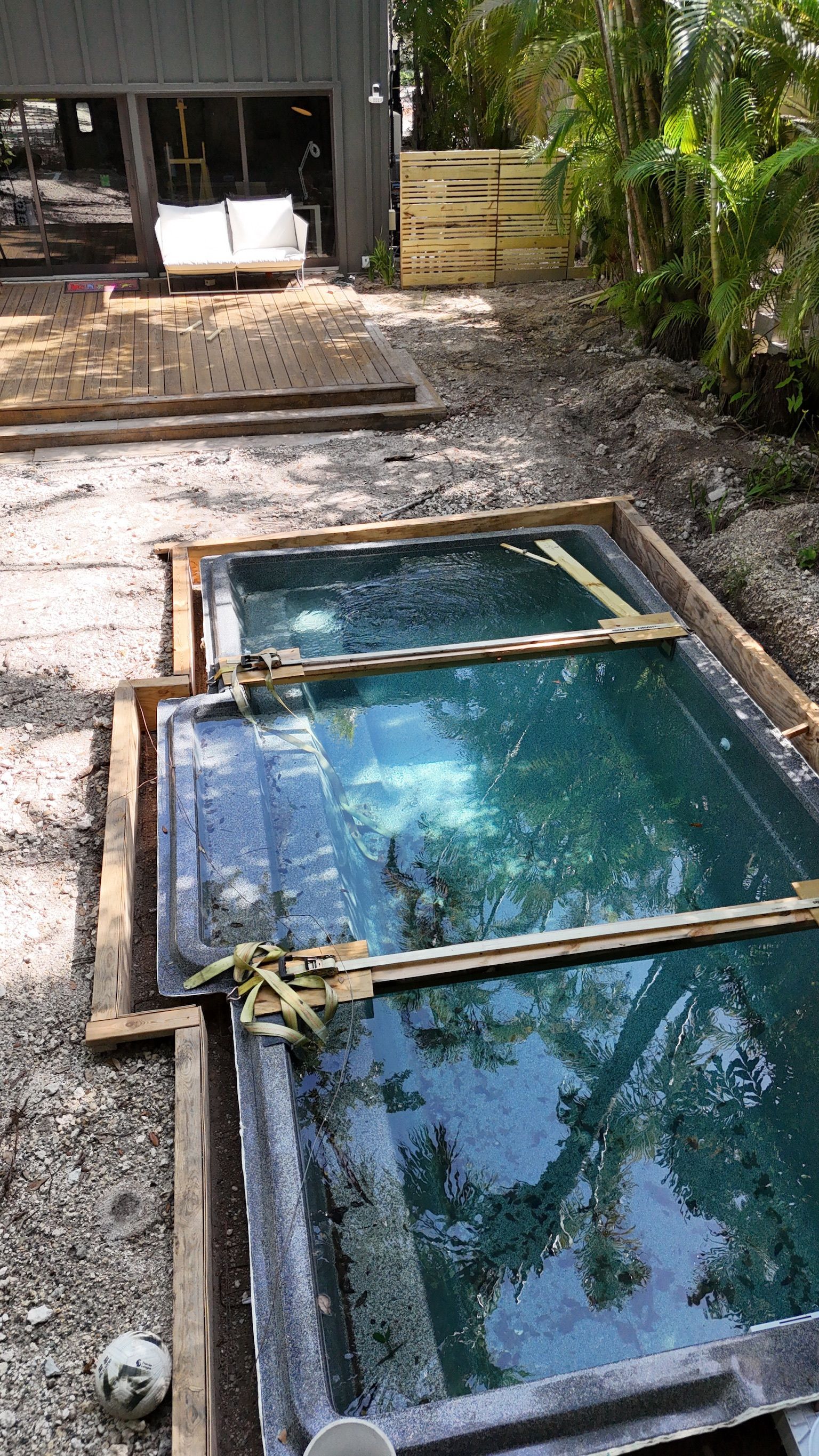 A large swimming pool is being built in the backyard of a house.