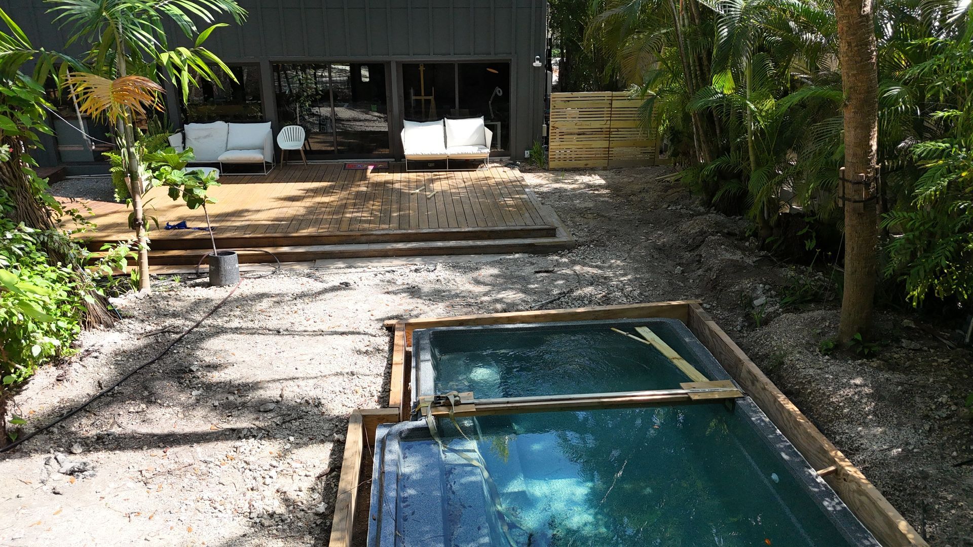 A large swimming pool is in the backyard of a house.