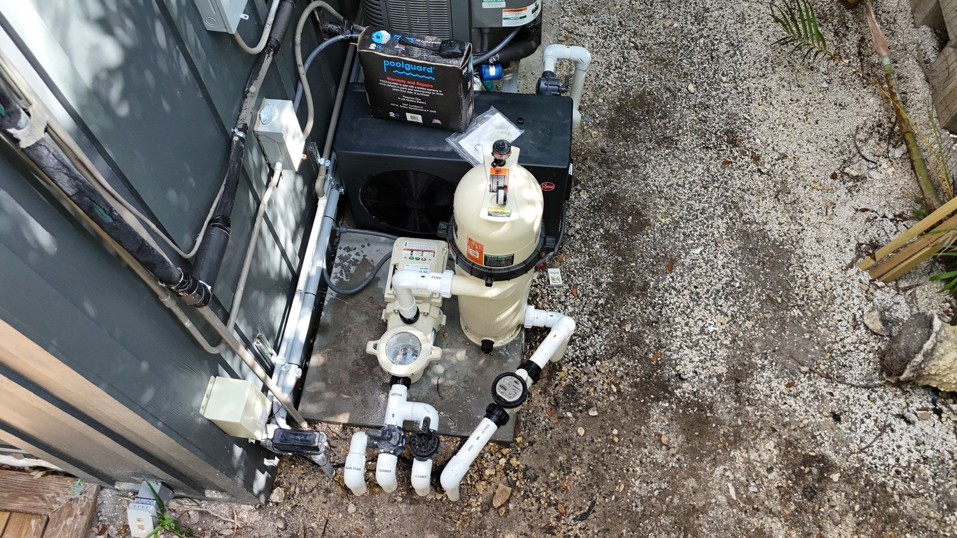 A swimming pool filter is sitting on the ground next to a building.