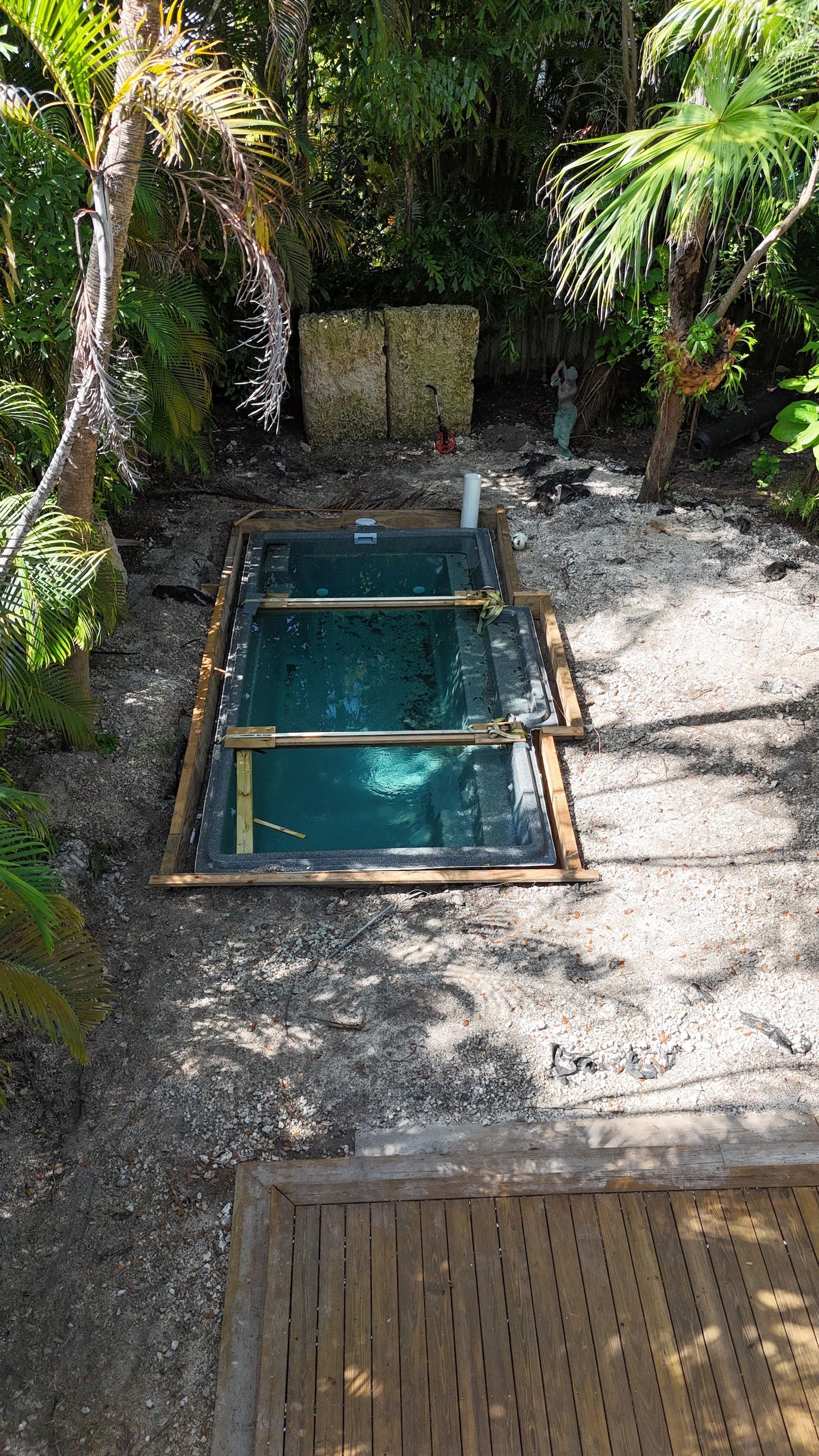 A small swimming pool is being built in the middle of a lush green forest.