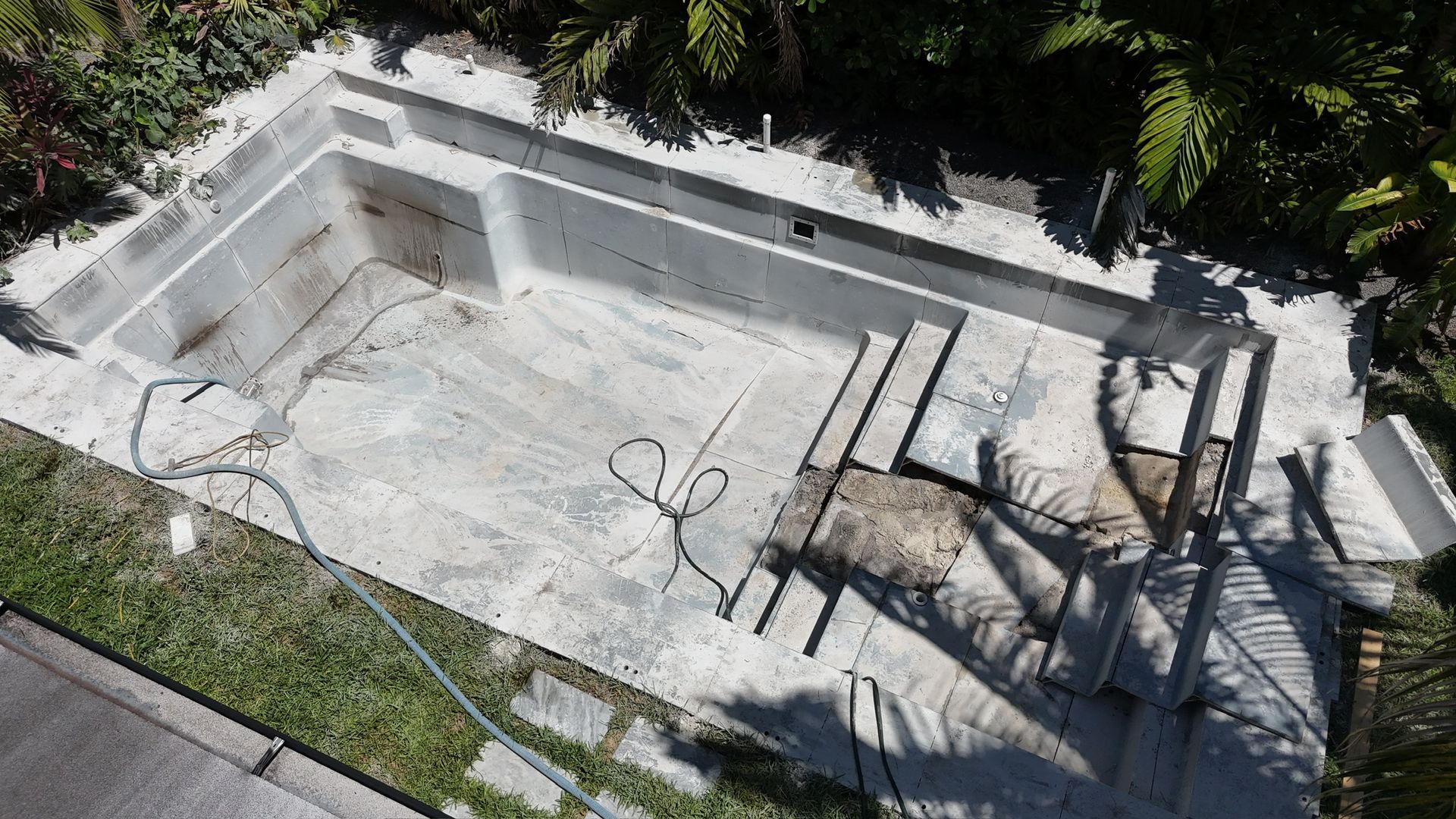 An aerial view of an empty swimming pool in a backyard.