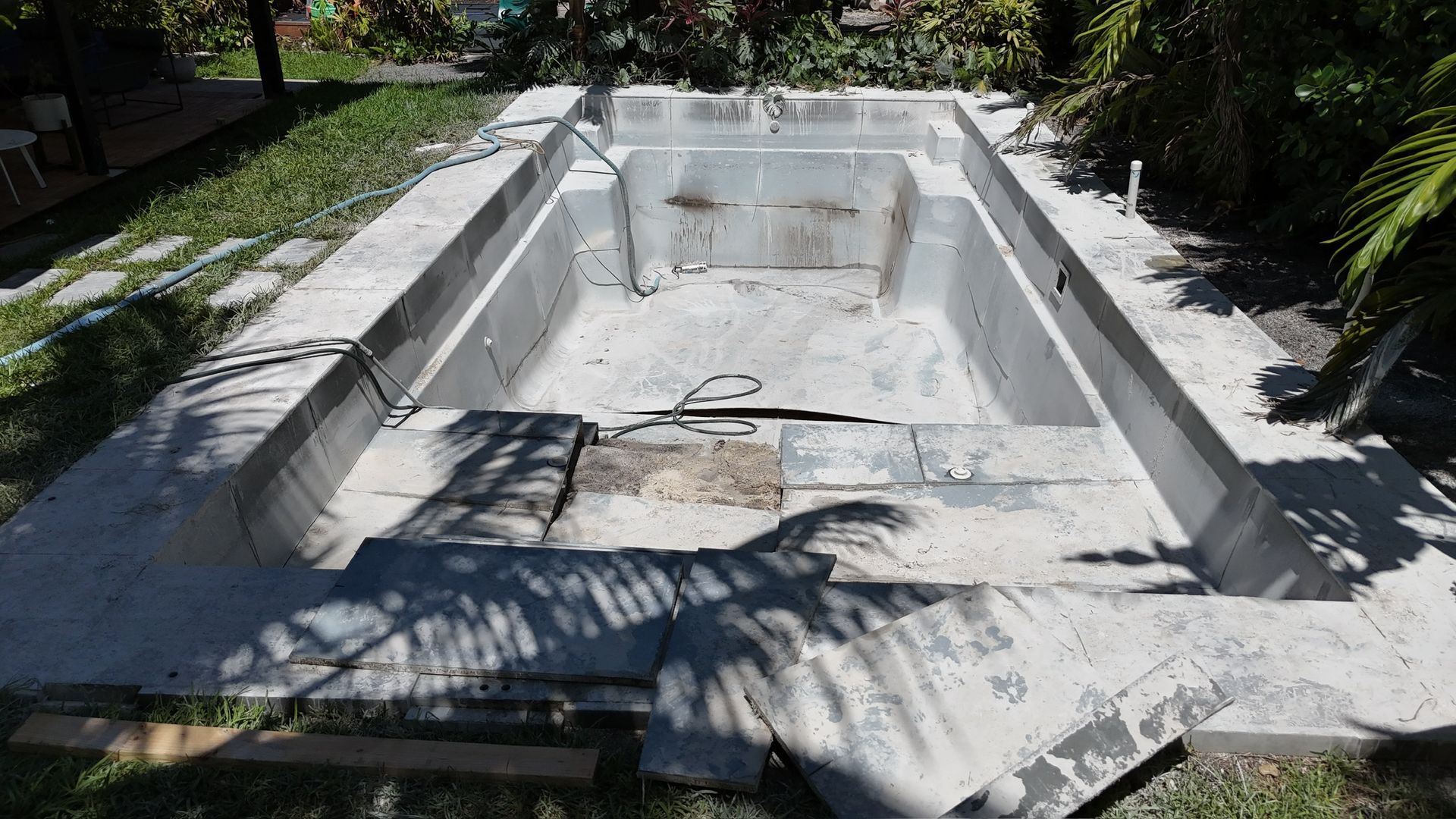 An empty swimming pool is being built in a backyard.