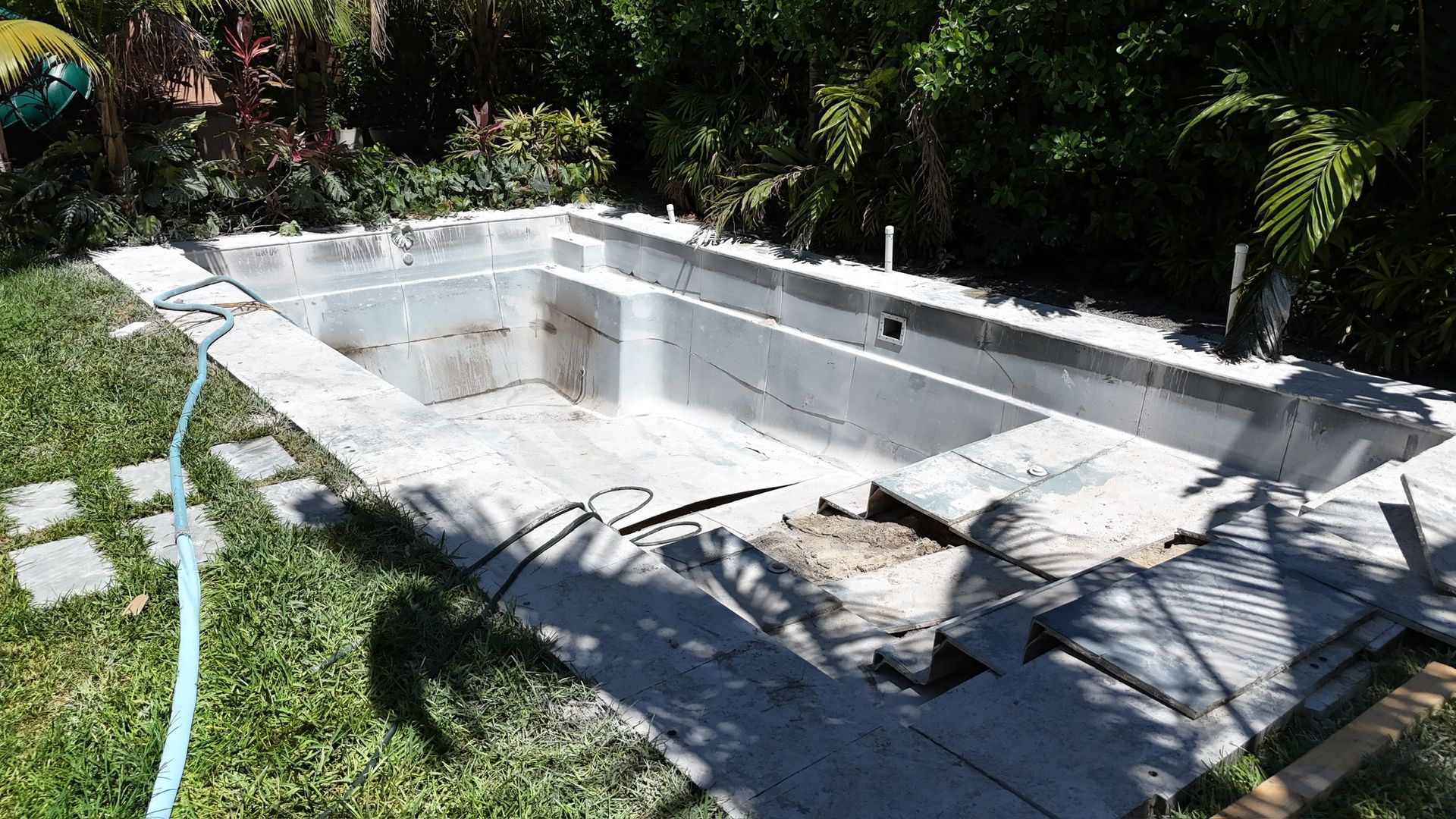 An empty swimming pool with a blue hose attached to it.