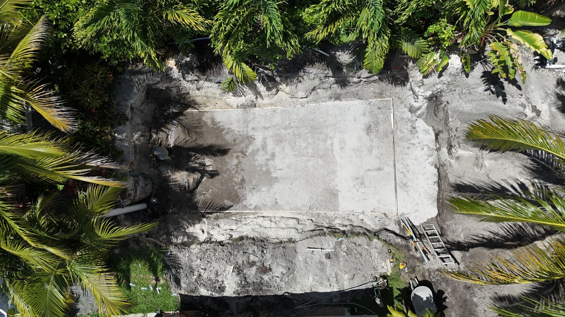 An aerial view of a concrete structure surrounded by palm trees.