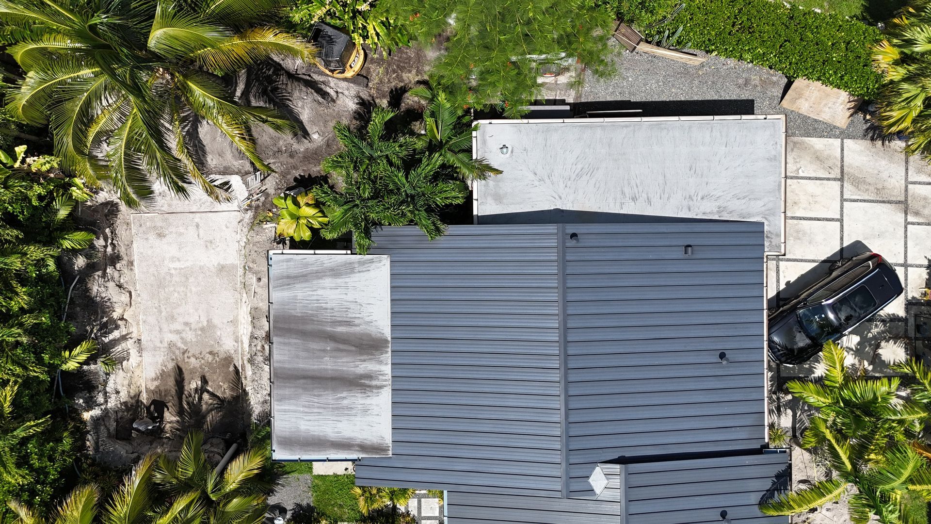 An aerial view of a house with a car parked in front of it surrounded by palm trees.