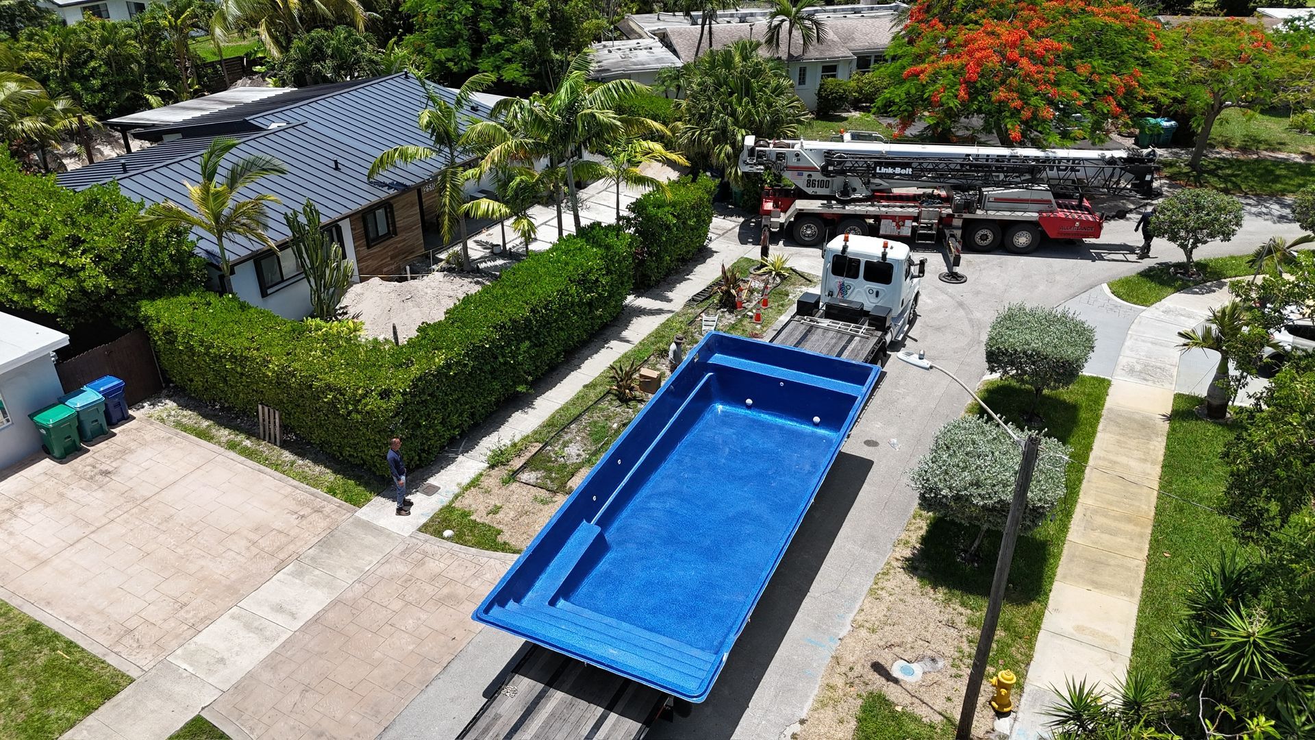 An aerial view of a large blue swimming pool being loaded on a truck.