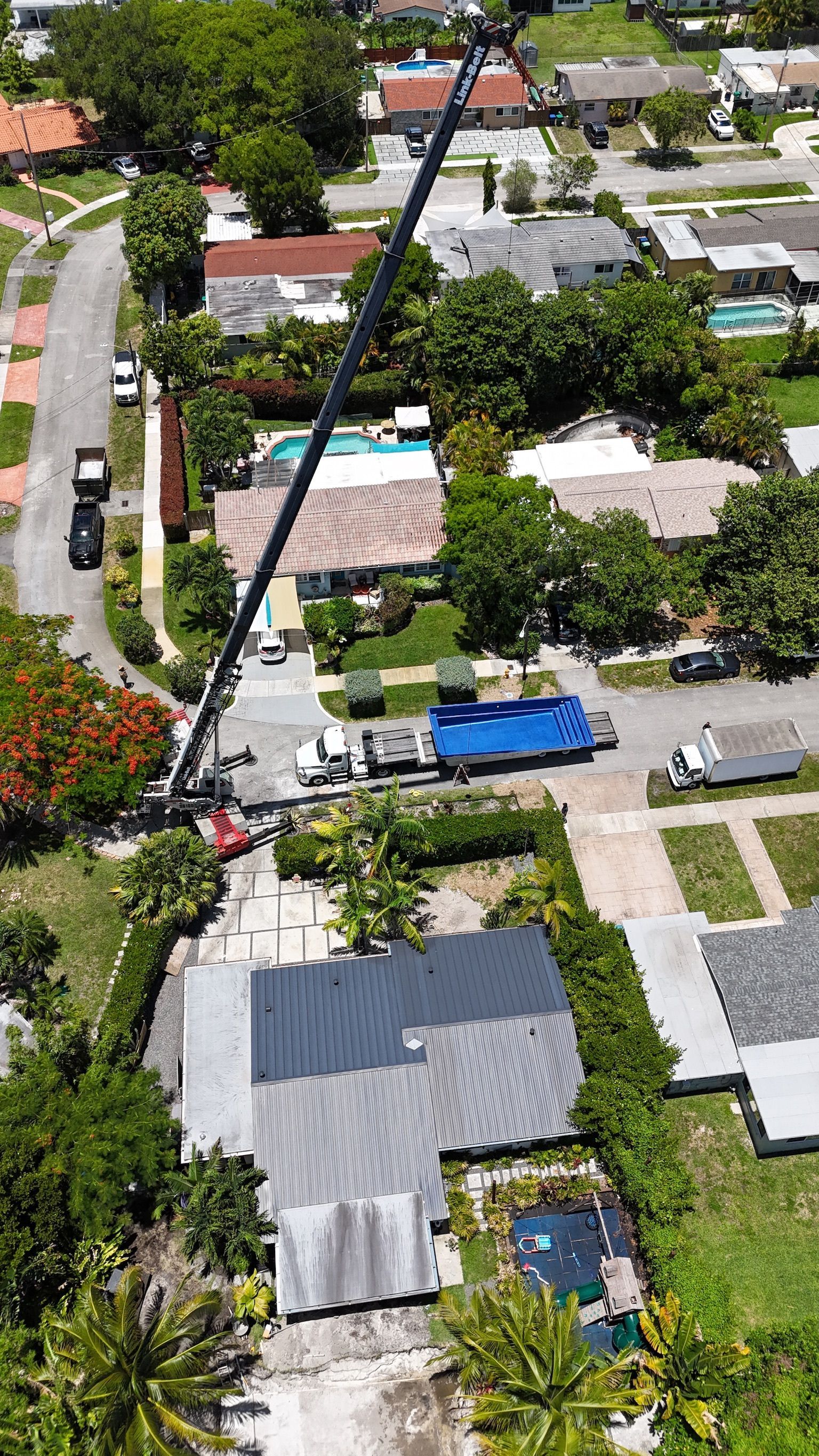 An aerial view of a crane lifting a house in a residential area.