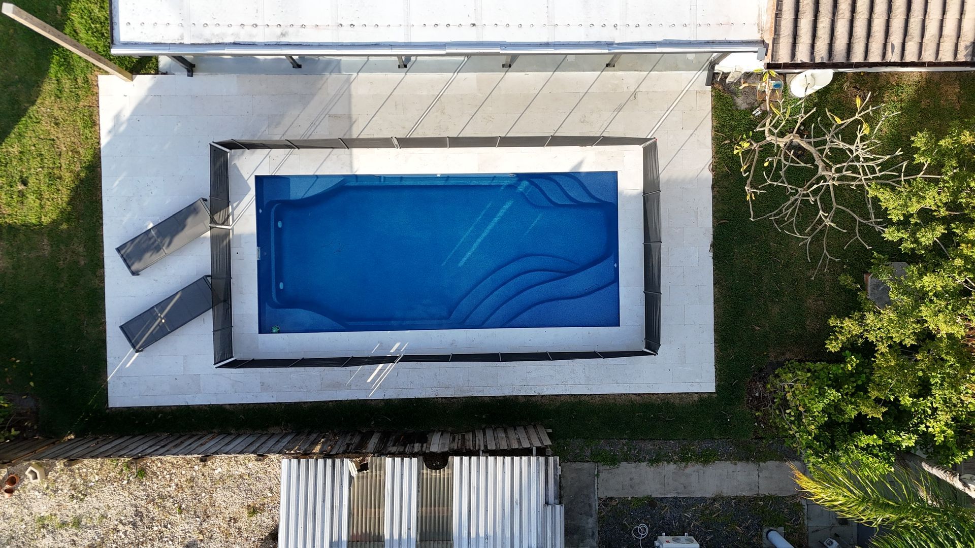 An aerial view of a swimming pool in the backyard of a house.