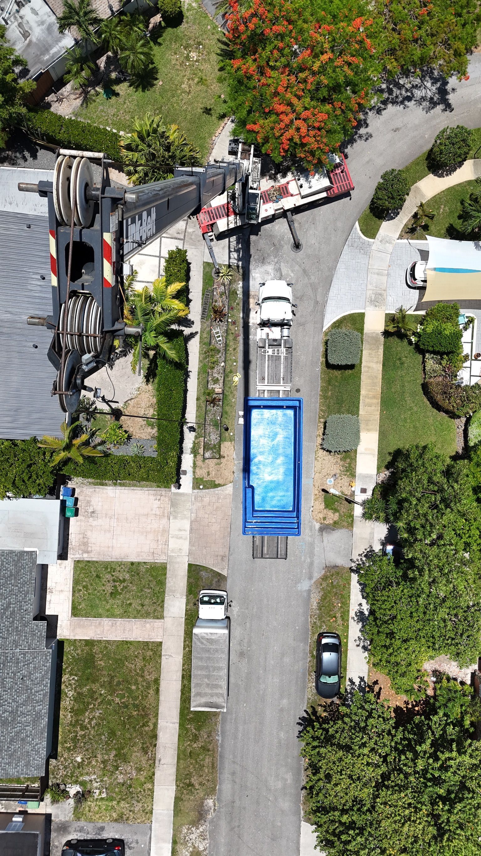 An aerial view of a truck carrying a swimming pool down a street.