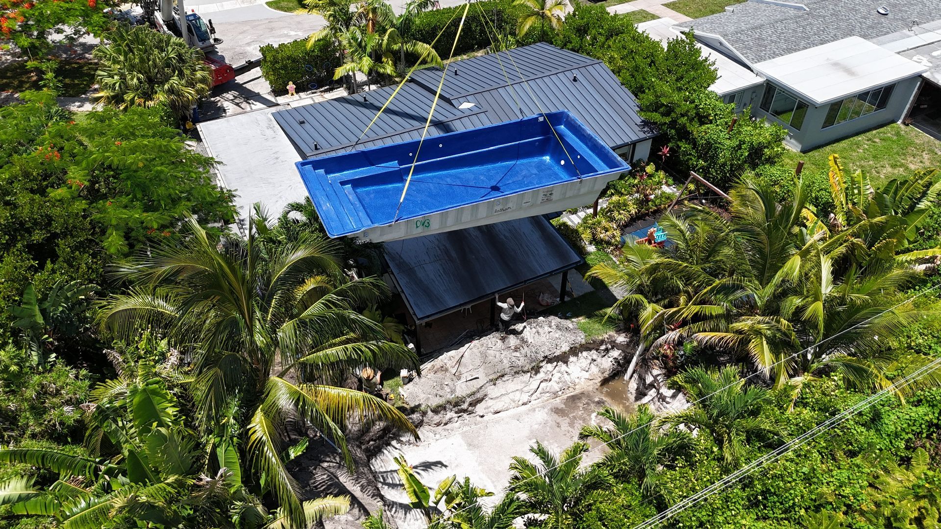 An aerial view of a house with a large swimming pool surrounded by trees.