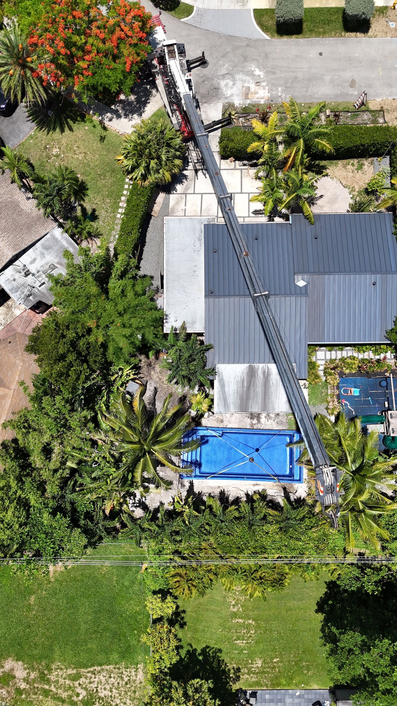 An aerial view of a house with a pool and a crane in front of it.