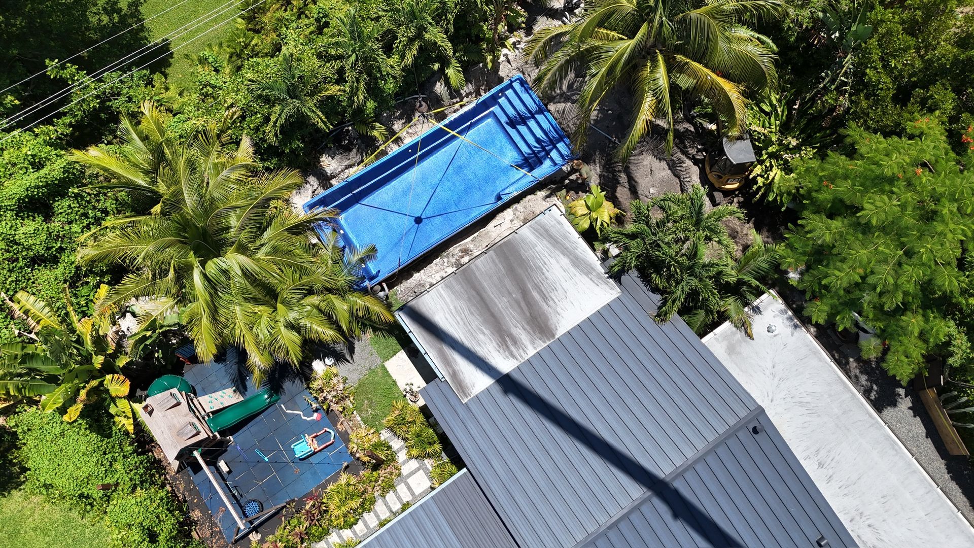 An aerial view of a house with a swimming pool and solar panels.