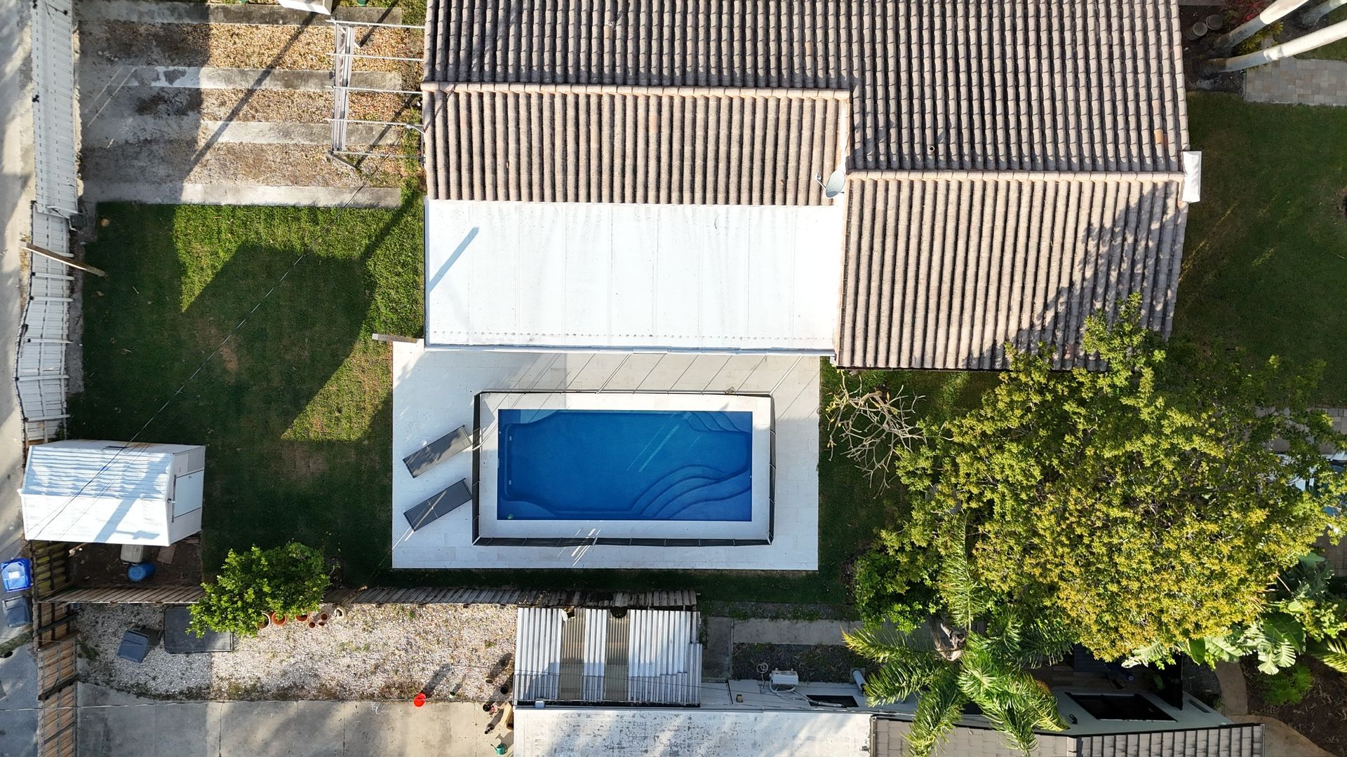 An aerial view of a house with a swimming pool in the backyard.