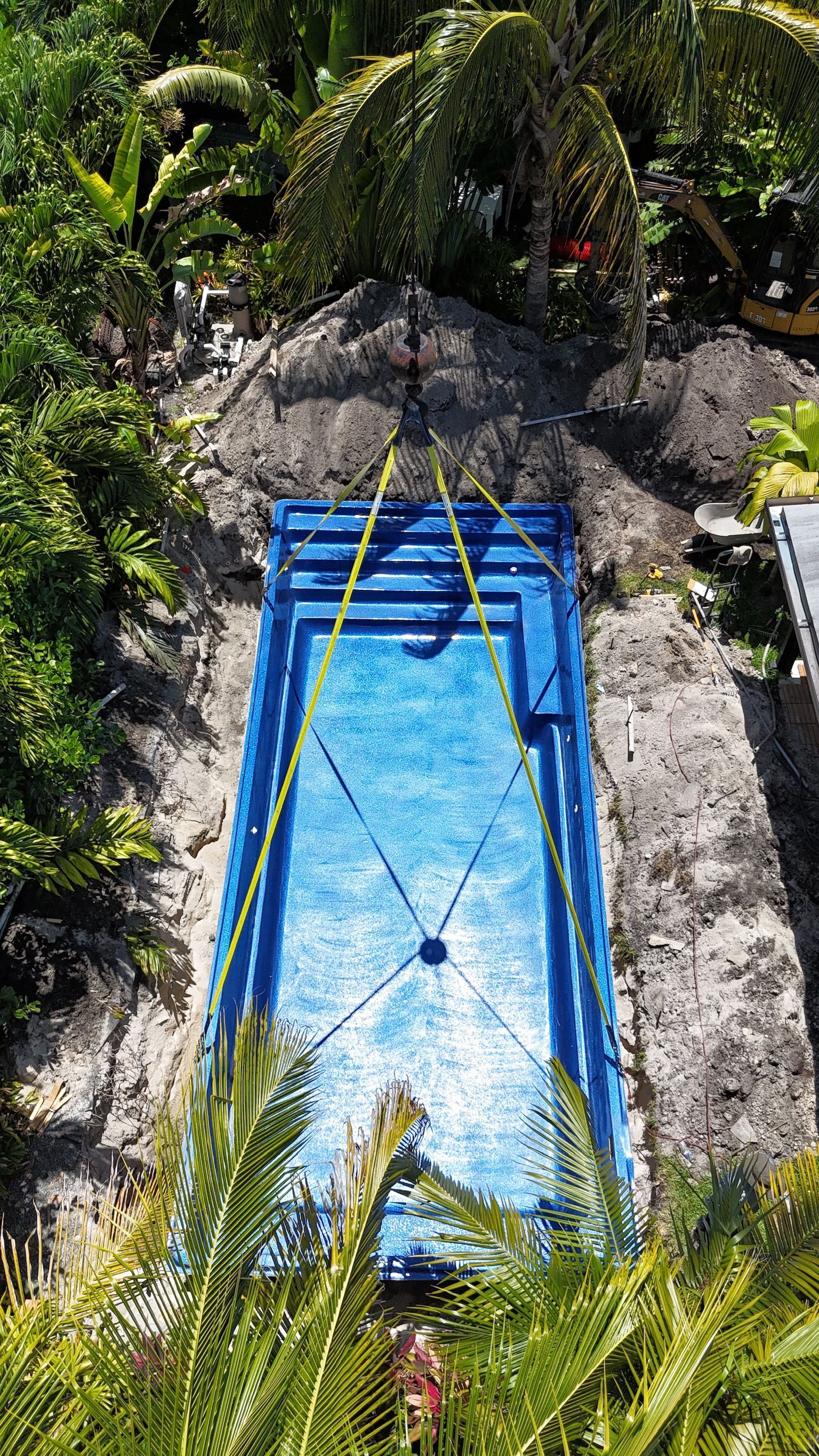 An aerial view of a blue swimming pool surrounded by trees.