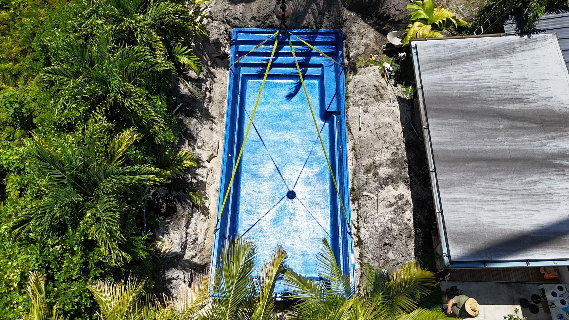 An aerial view of a swimming pool being built in a backyard.