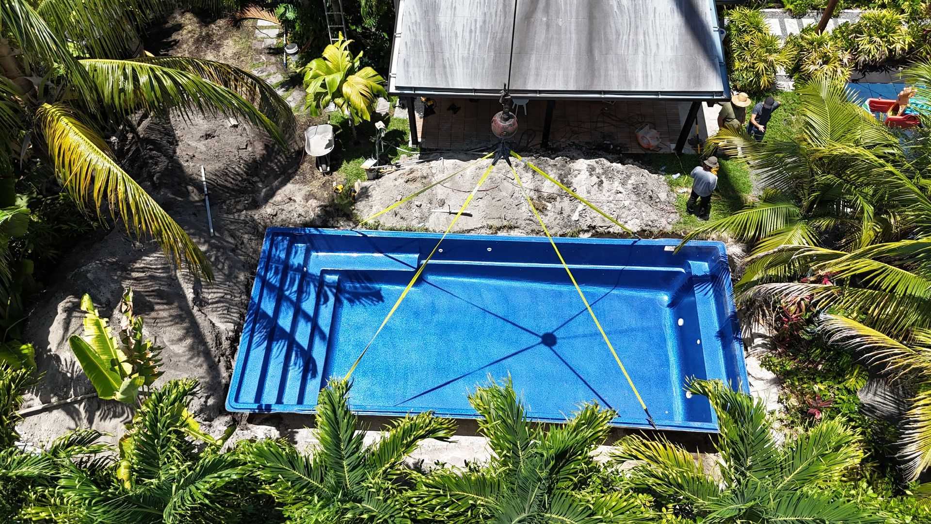 An aerial view of a large blue swimming pool surrounded by trees.