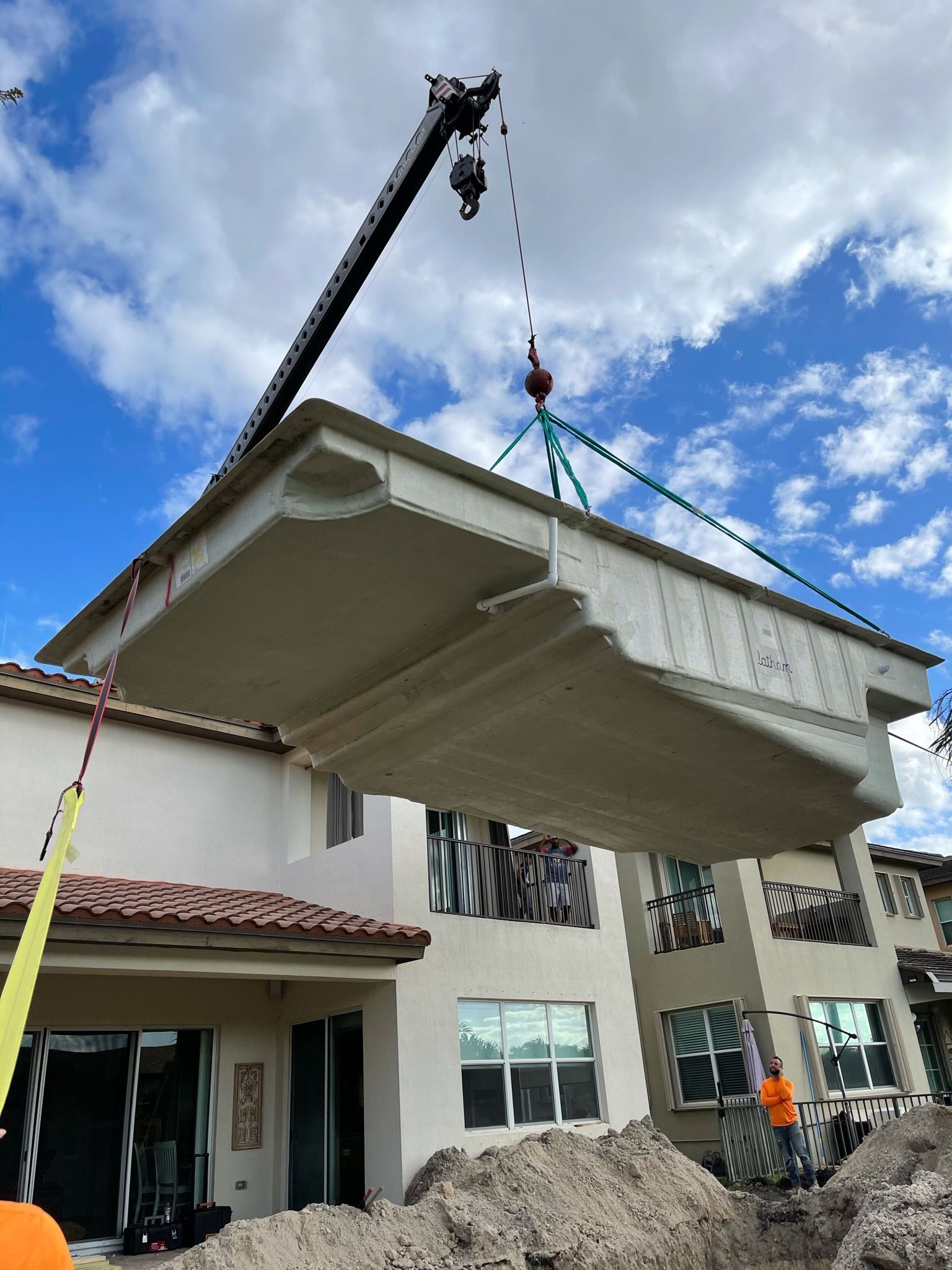A crane is lifting a pool over a house