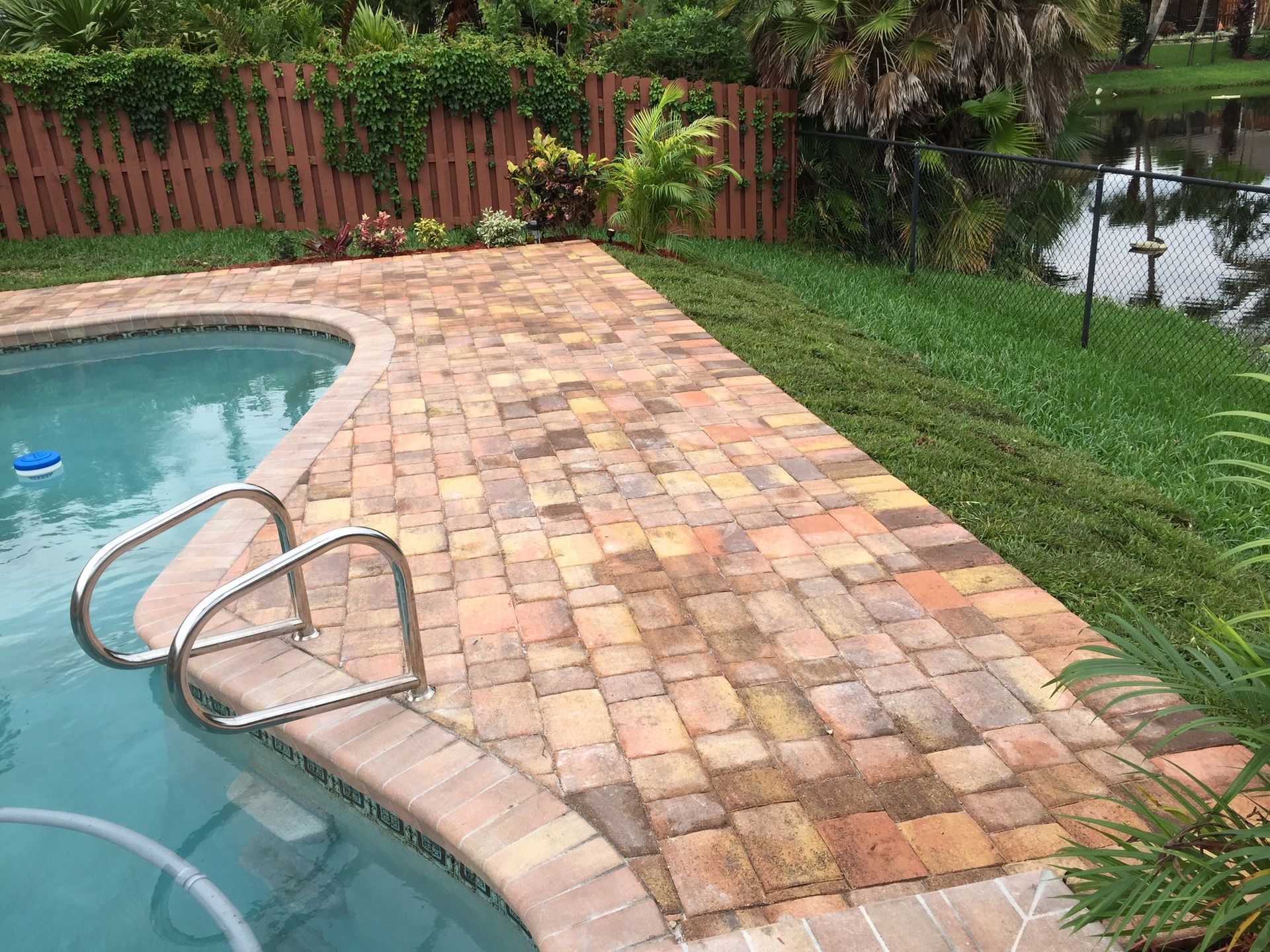 A swimming pool with a brick patio and stairs leading to it.
