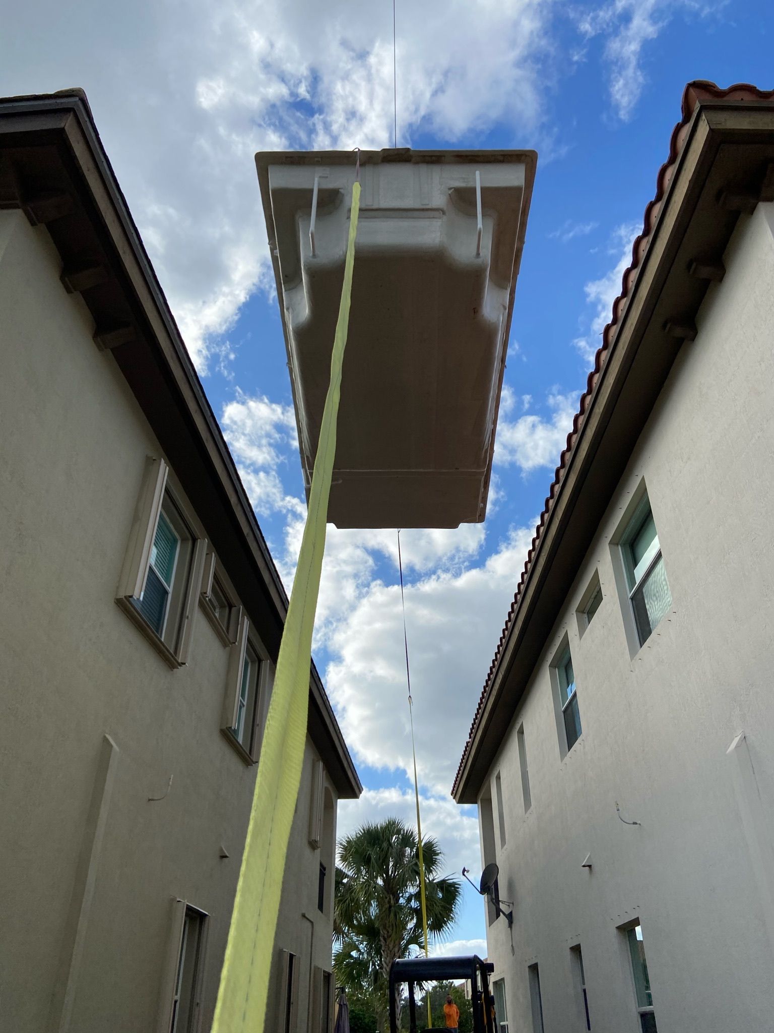 A crane is lifting a roof between two buildings