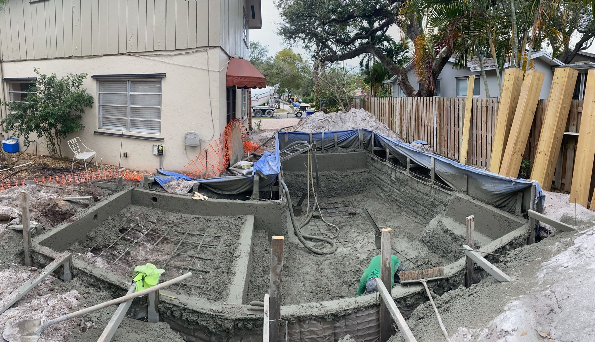 A swimming pool is being built in the backyard of a house.