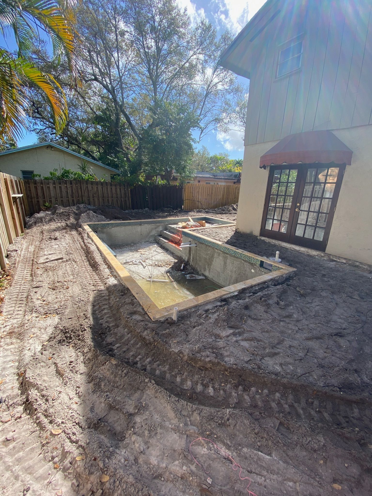 A swimming pool is being built in the backyard of a house.