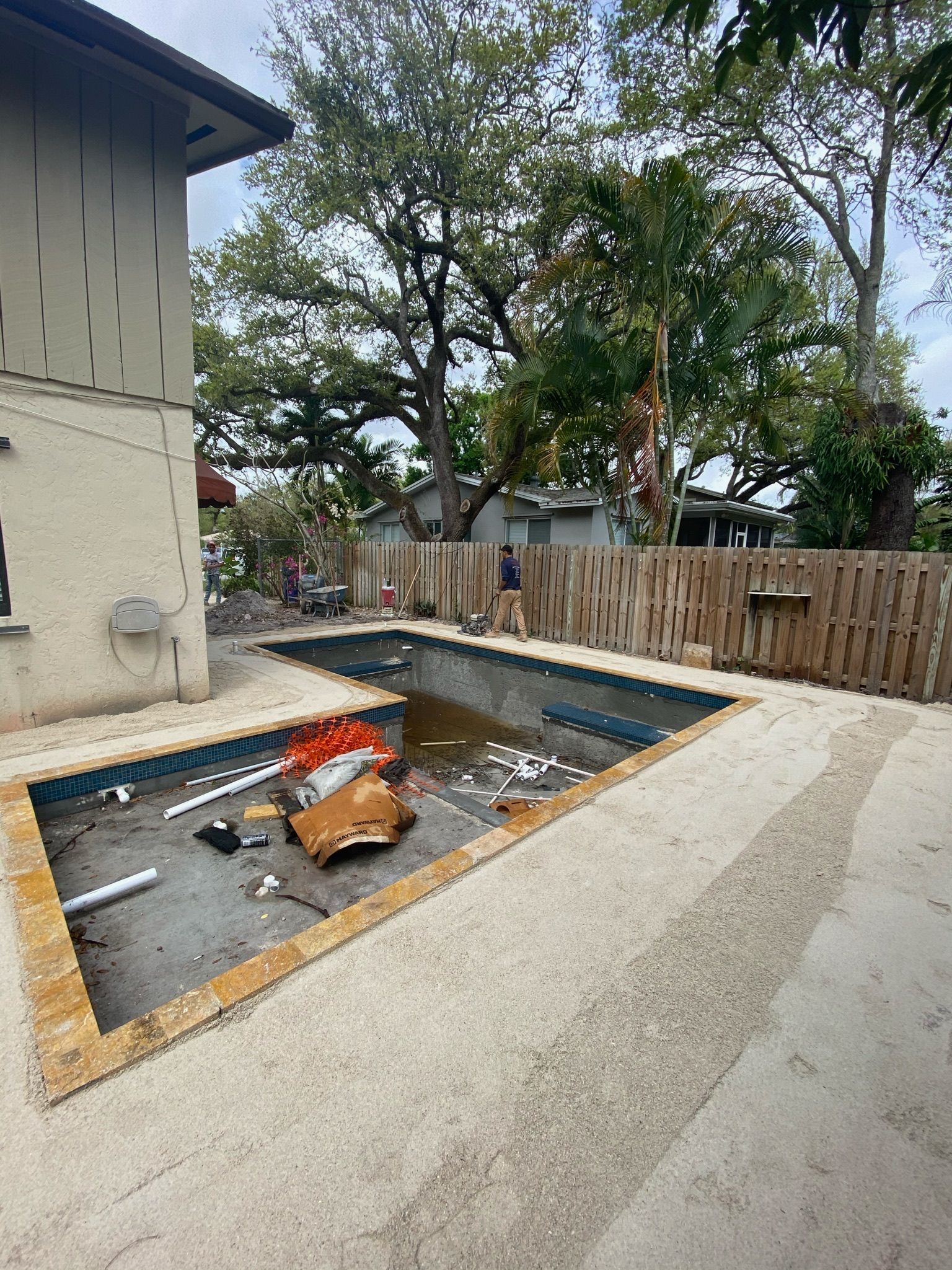 A swimming pool is being built in the backyard of a house.