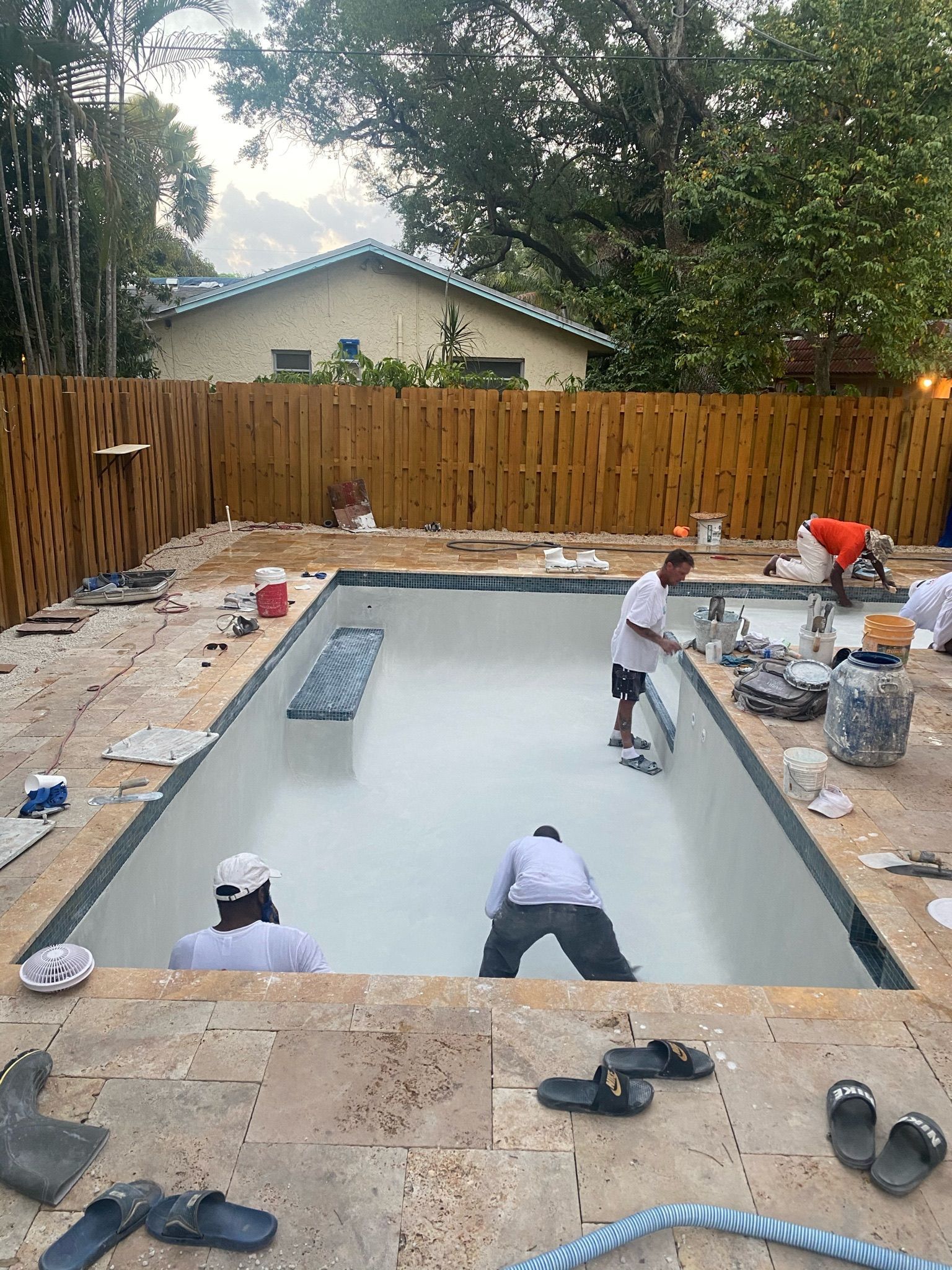A group of men are working on a swimming pool in a backyard.
