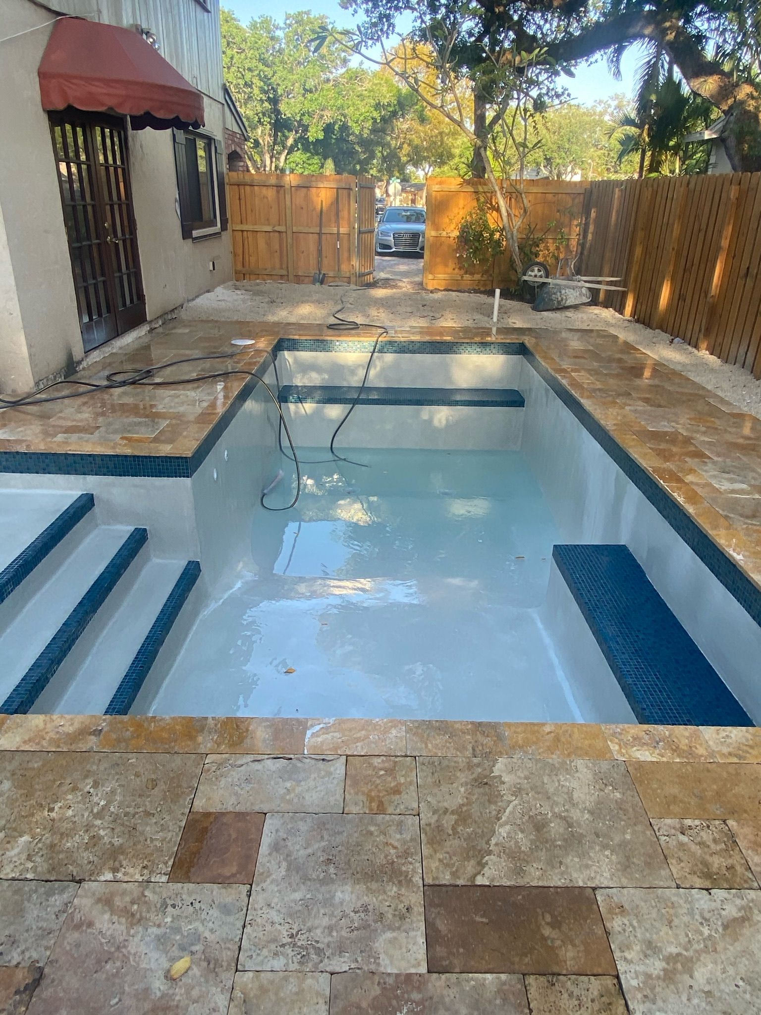 A swimming pool is being built in the backyard of a house.