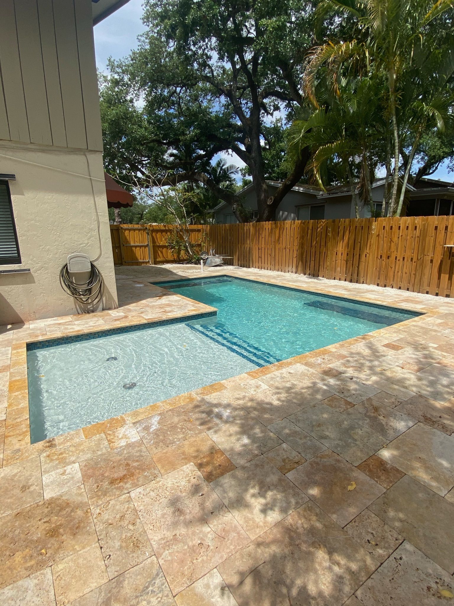 There is a large swimming pool in the backyard of a house.
