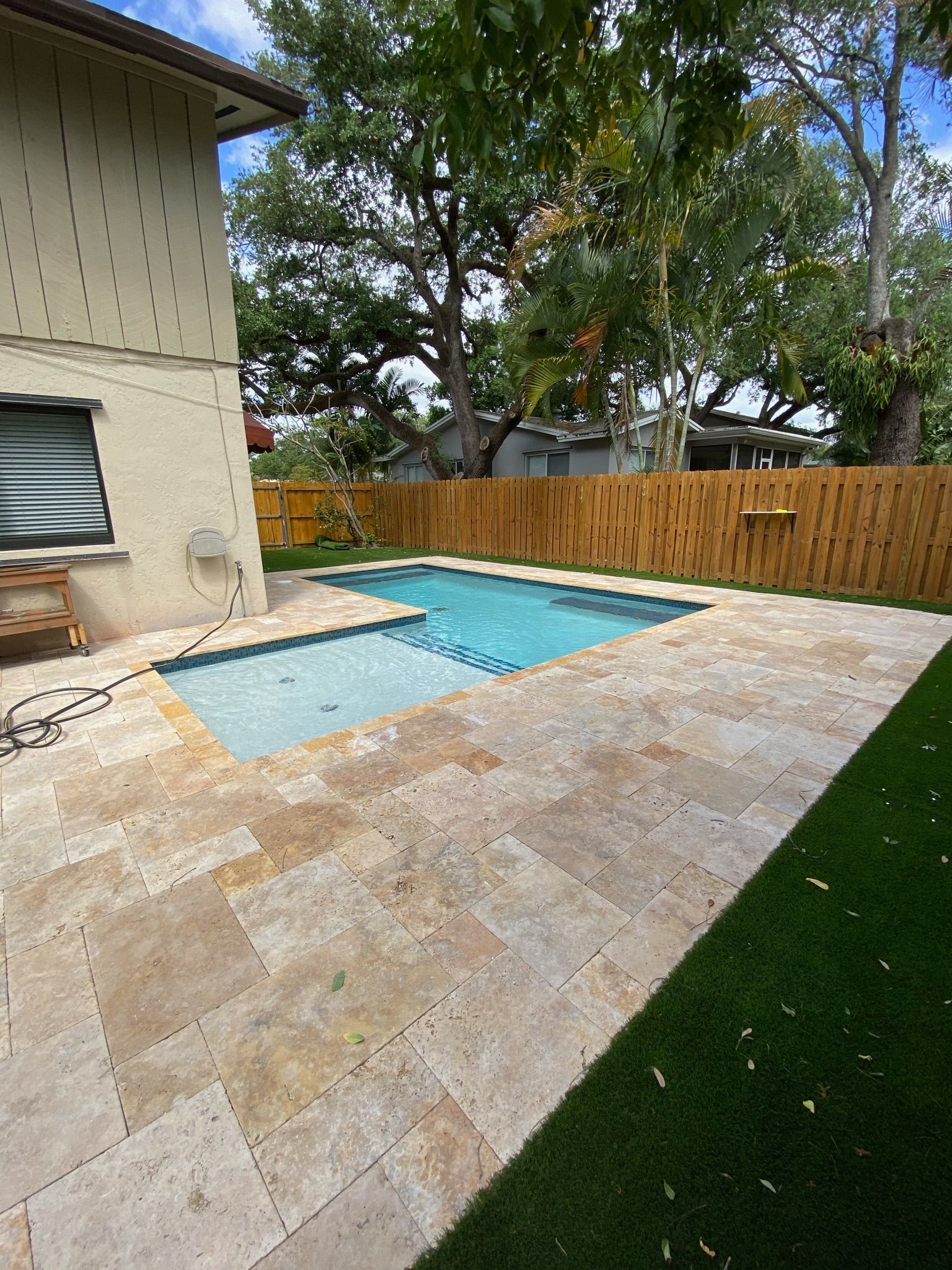 A large swimming pool is in the backyard of a house.