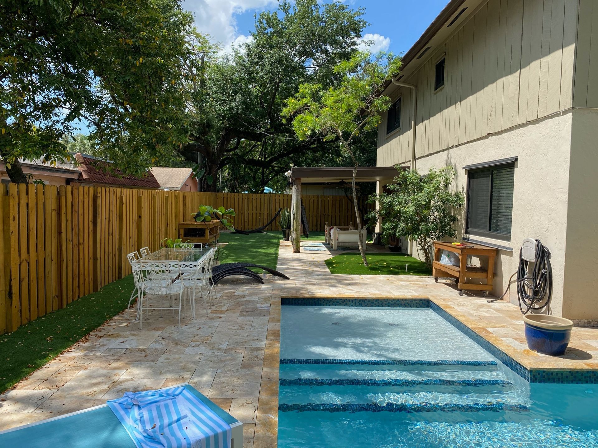 There is a large swimming pool in the backyard of a house.
