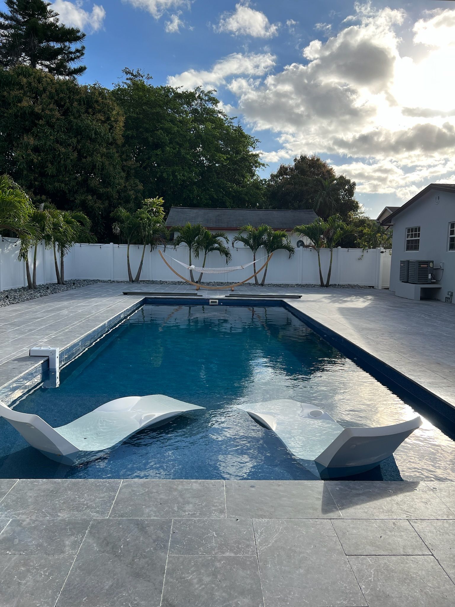 A large swimming pool with two lounge chairs in it