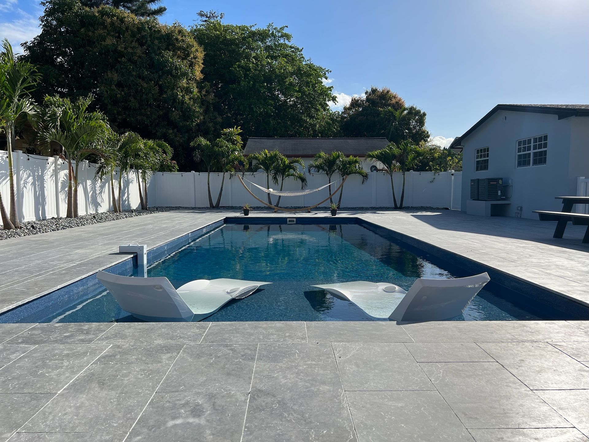 A large swimming pool with chairs and a hammock