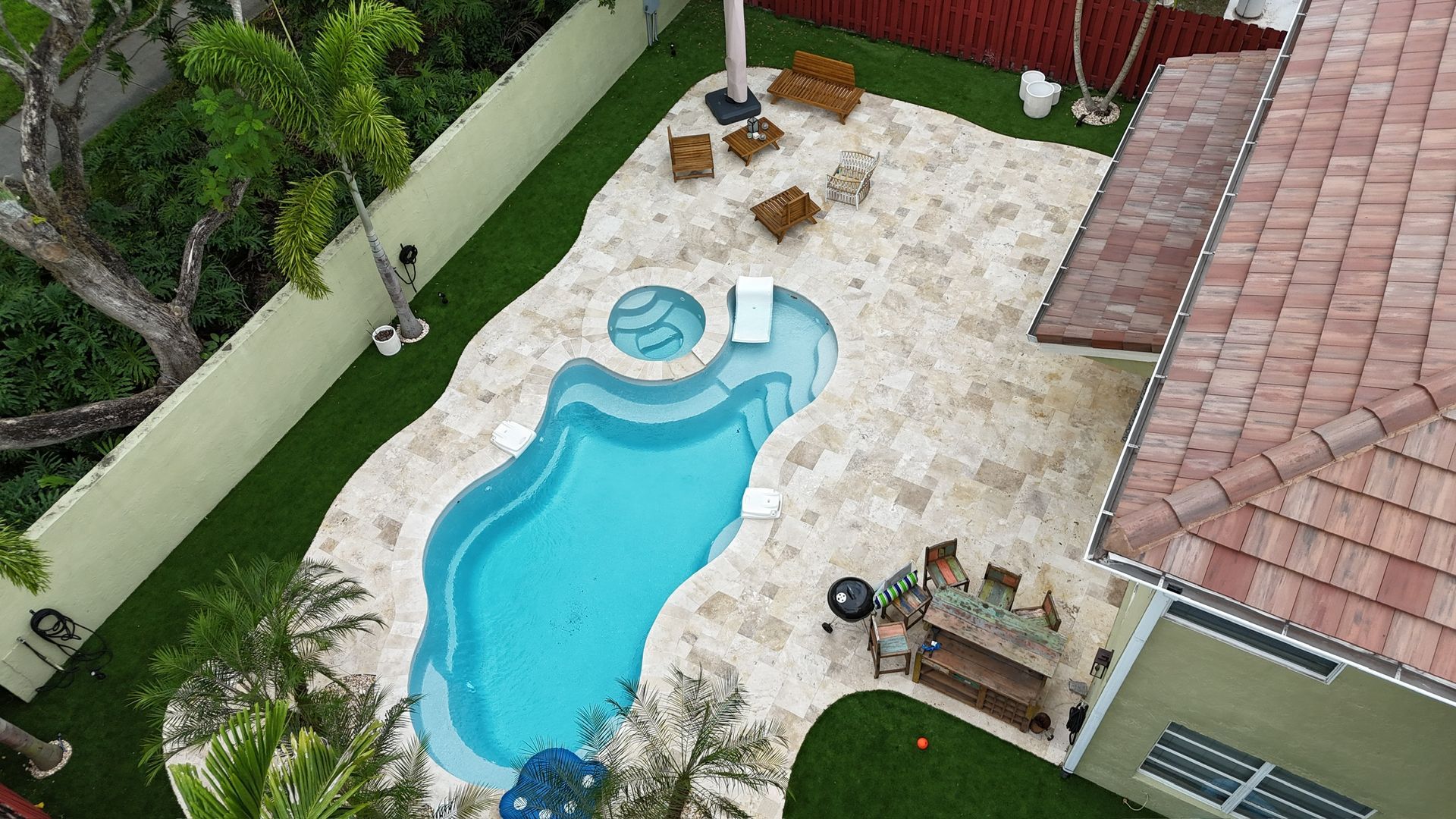 An aerial view of a house with a large swimming pool in the backyard.