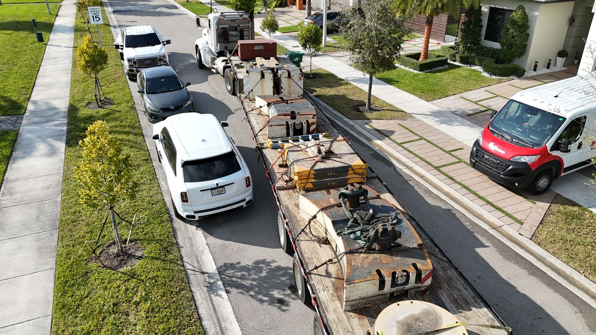 An aerial view of a truck carrying a tank down a street.