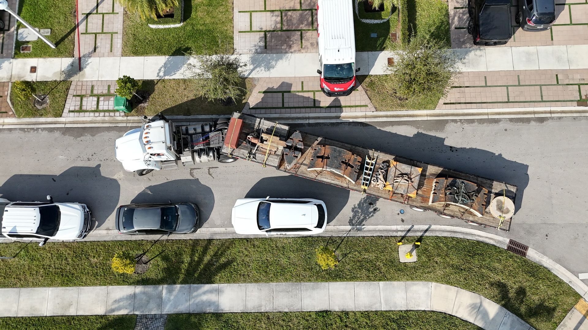 An aerial view of a row of cars parked on the side of a street.