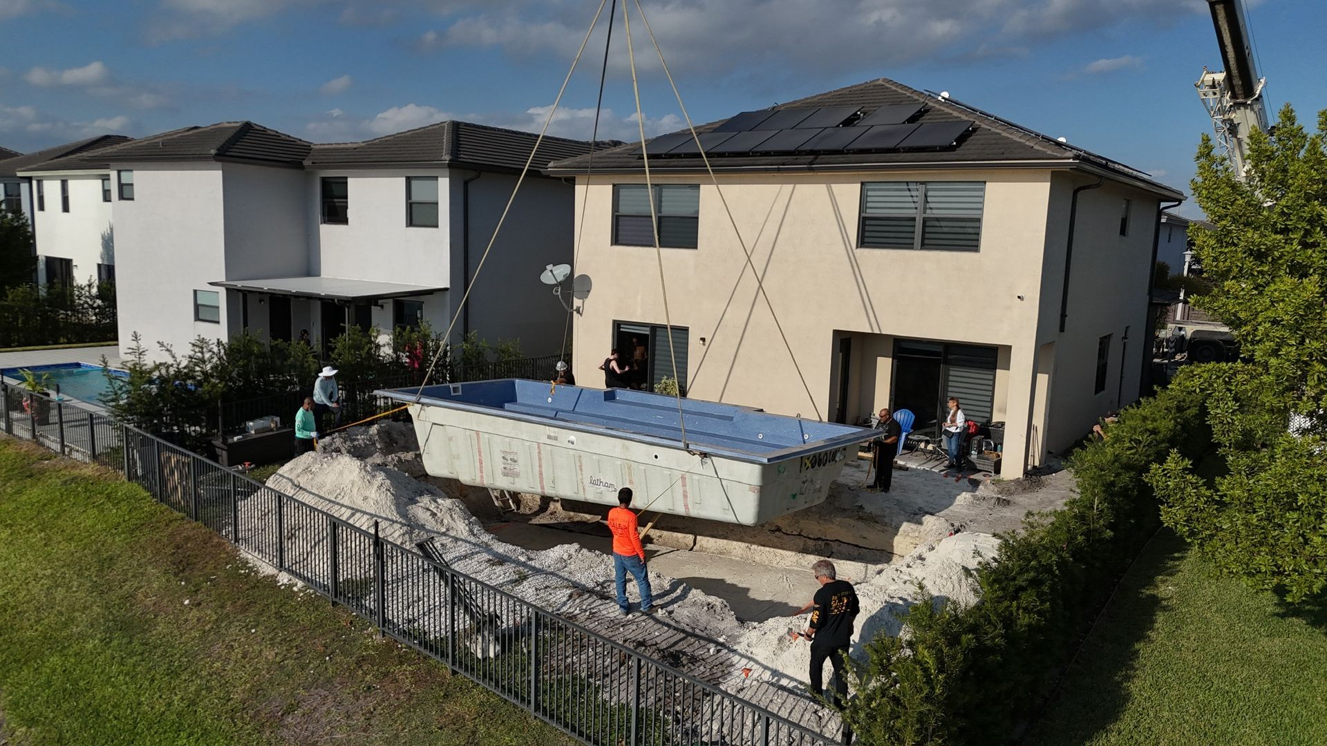 A large swimming pool is being built in front of a house.