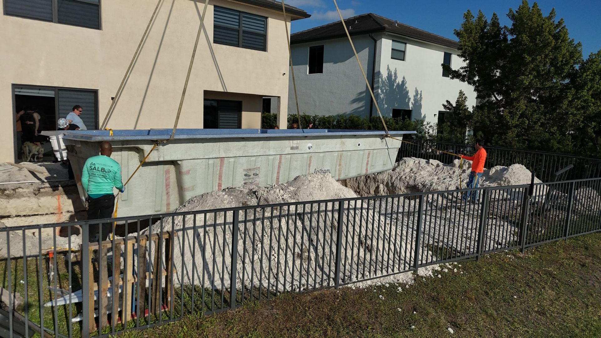 A large swimming pool is being built in front of a house.