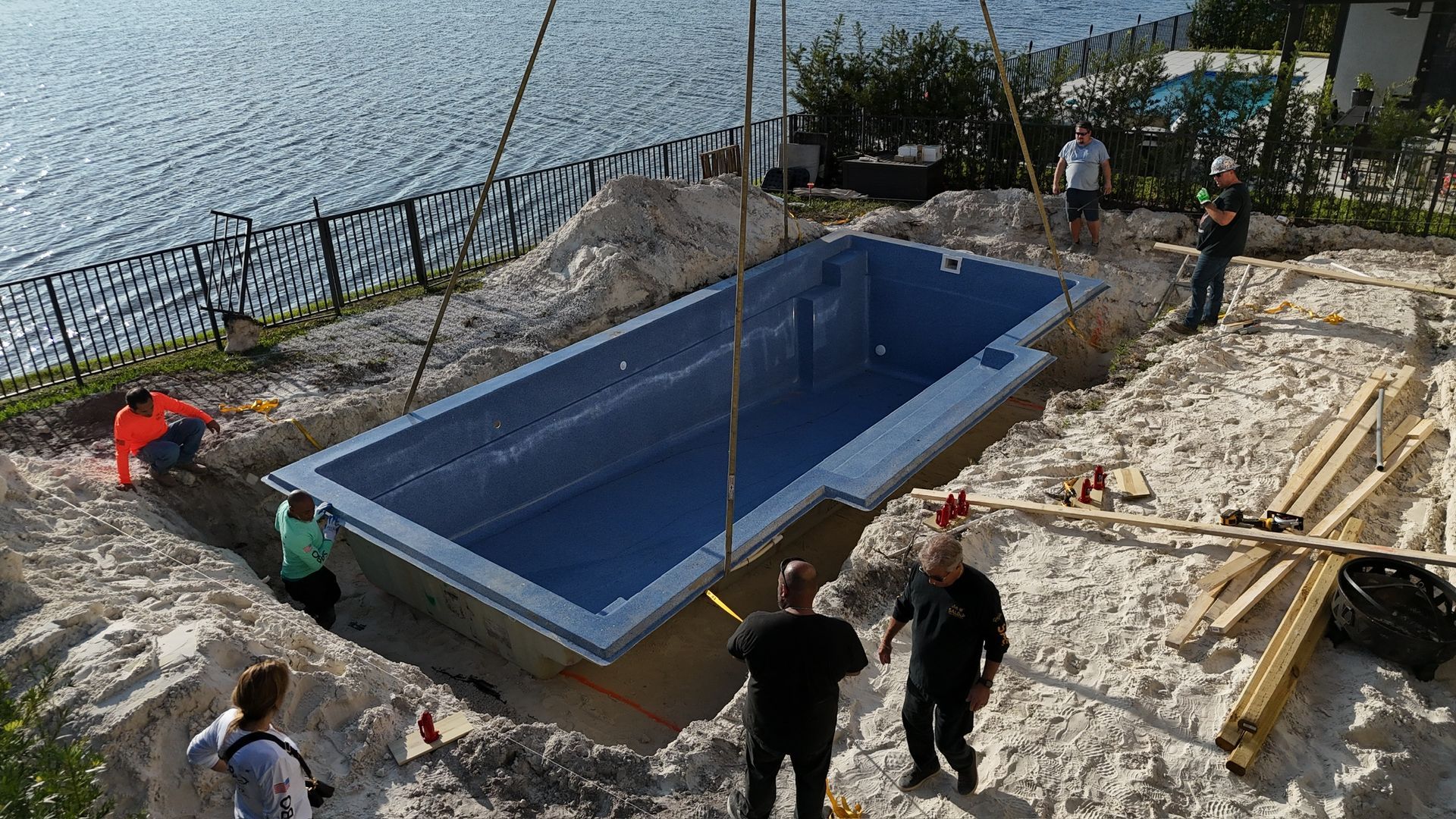 A large swimming pool is being lifted into the ground by a crane.