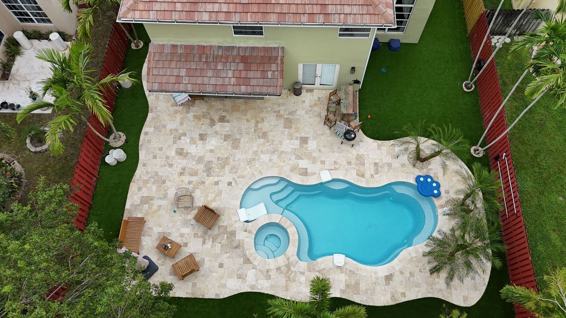 An aerial view of a house with a large swimming pool in the backyard.