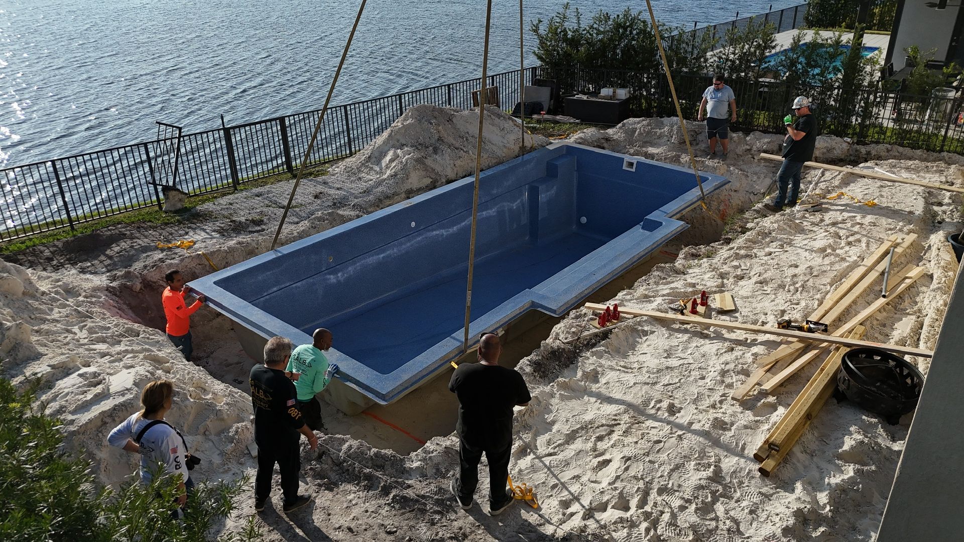 A group of people are standing around a large swimming pool being built.